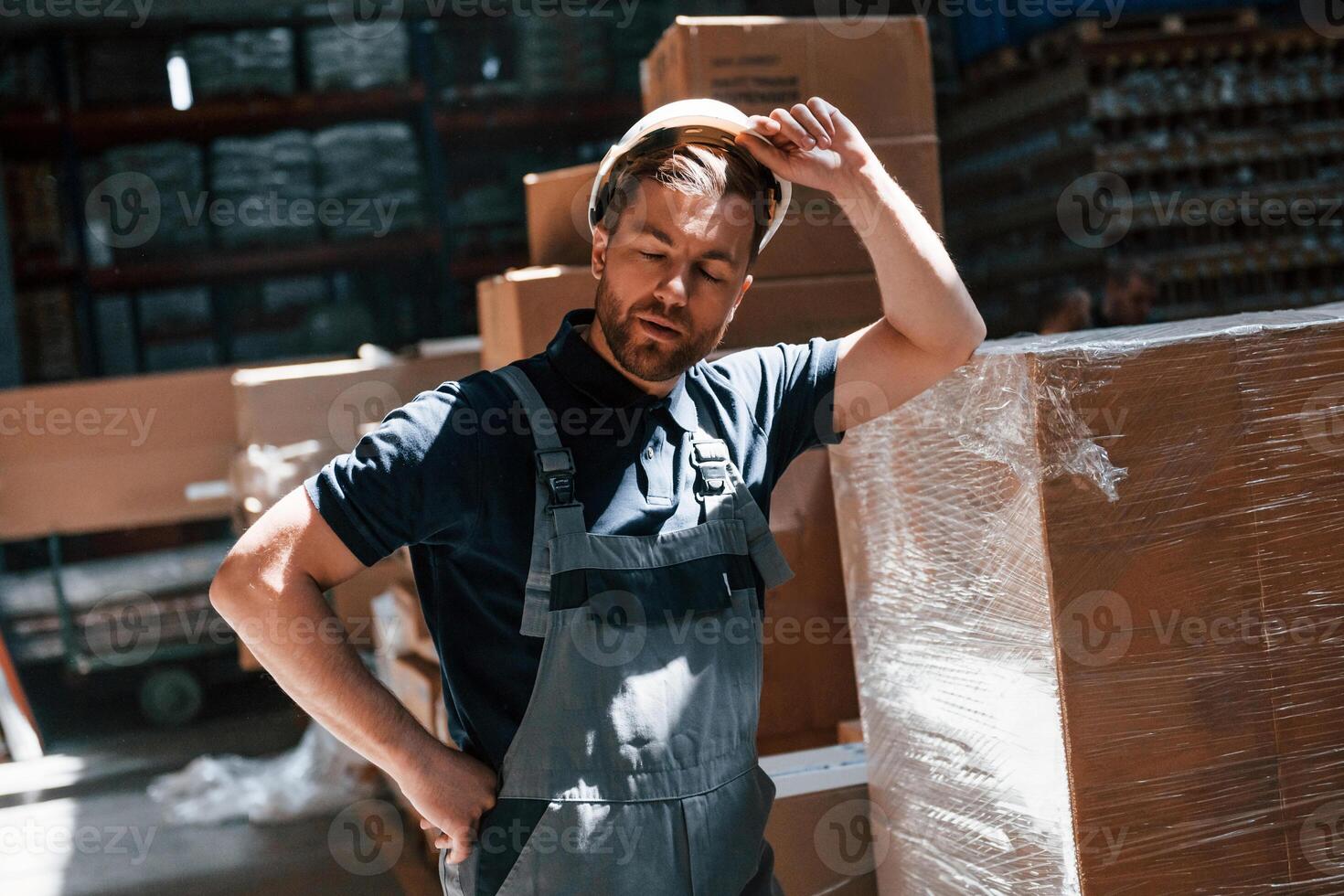 Tired employee in uniform is working in the dark storage photo