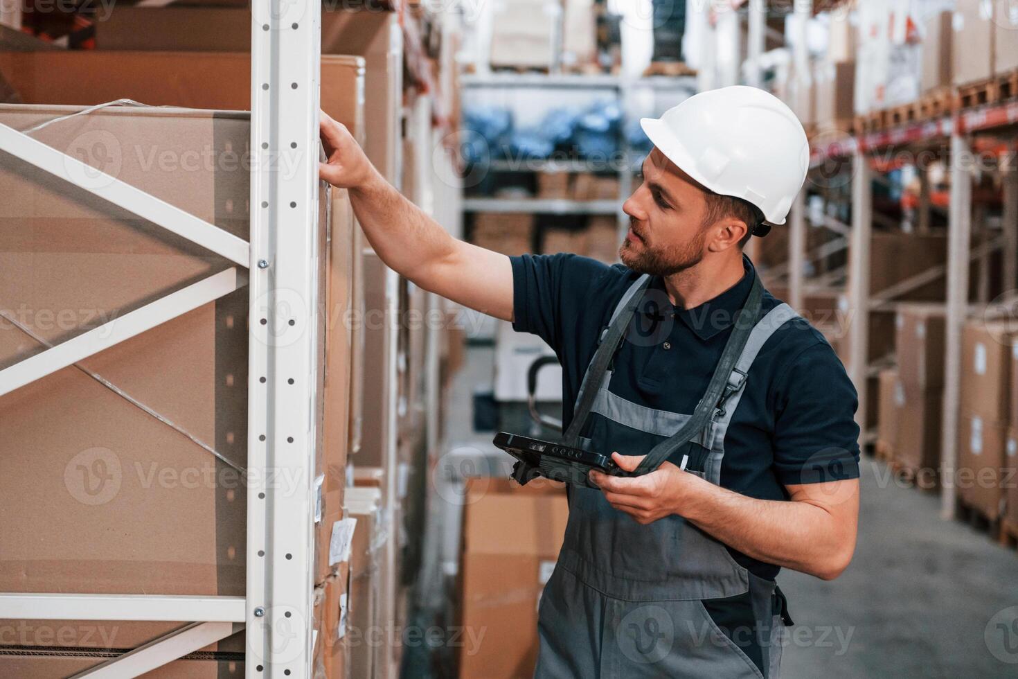 Checking the box. Employee in uniform is working in the storage at daytime. photo