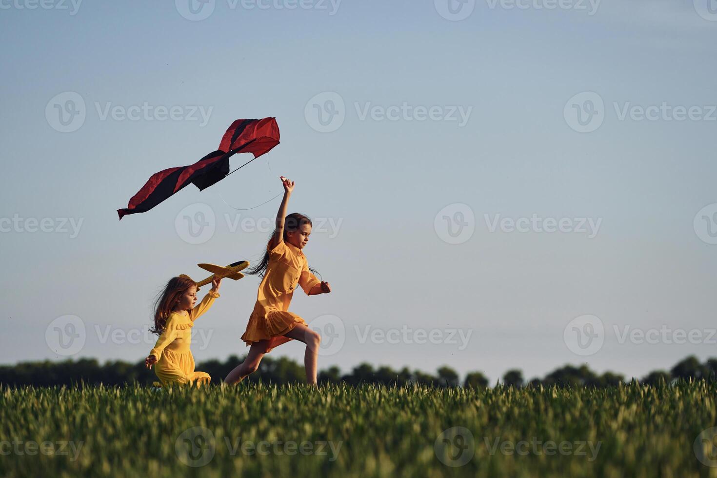 Running with kite.. Two girls have fun outdoors on the field at summer, photo