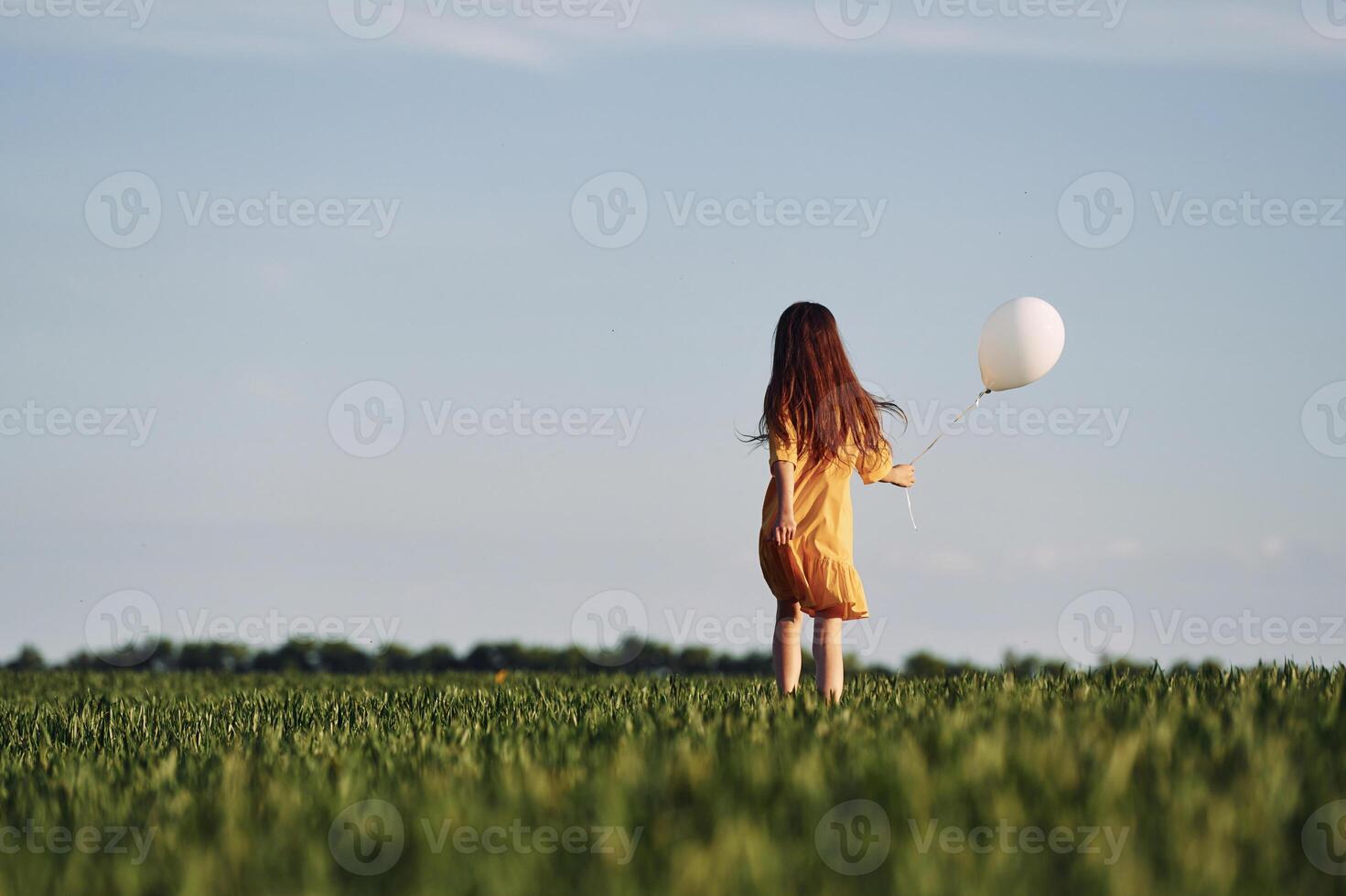 Running with balloon in hand.. Happy girl have a walk outdoors on the field at summer. photo
