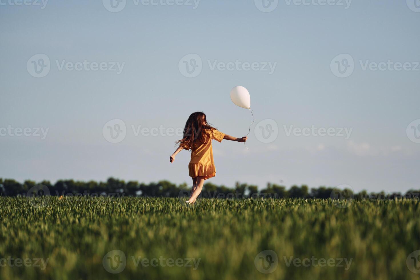 Running with balloon in hand.. Happy girl have a walk outdoors on the field at summer photo