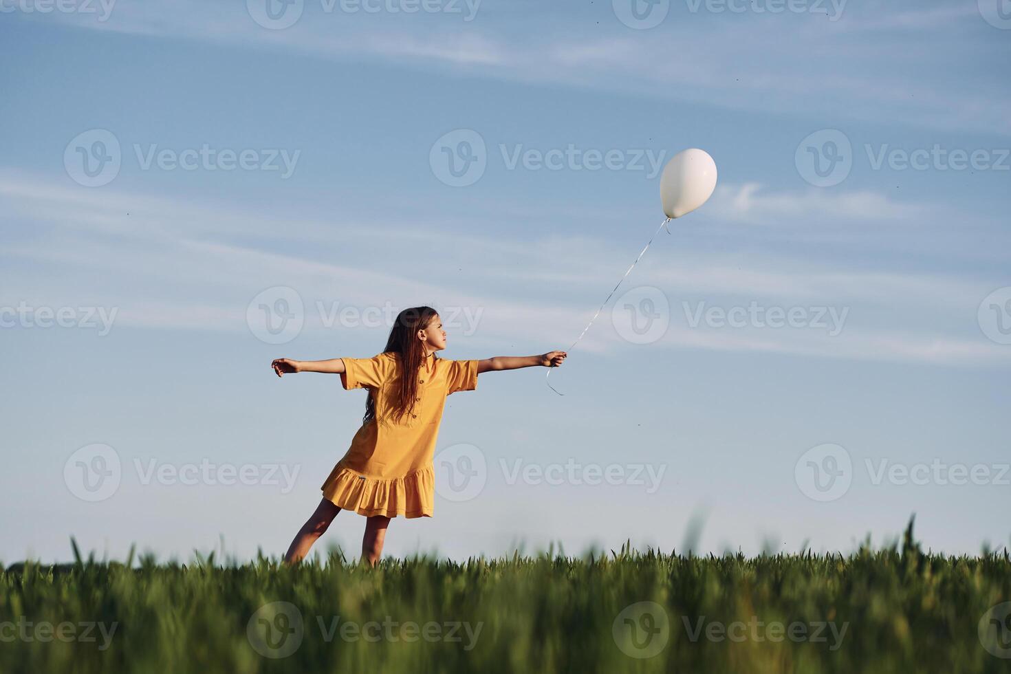 Playing with balloon. Happy girl have a walk outdoors on the field at summer.. photo