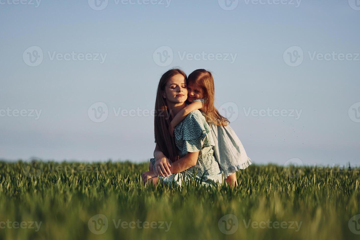 Clear sky. Mother and daughter have fun outdoors on the field at summer. photo
