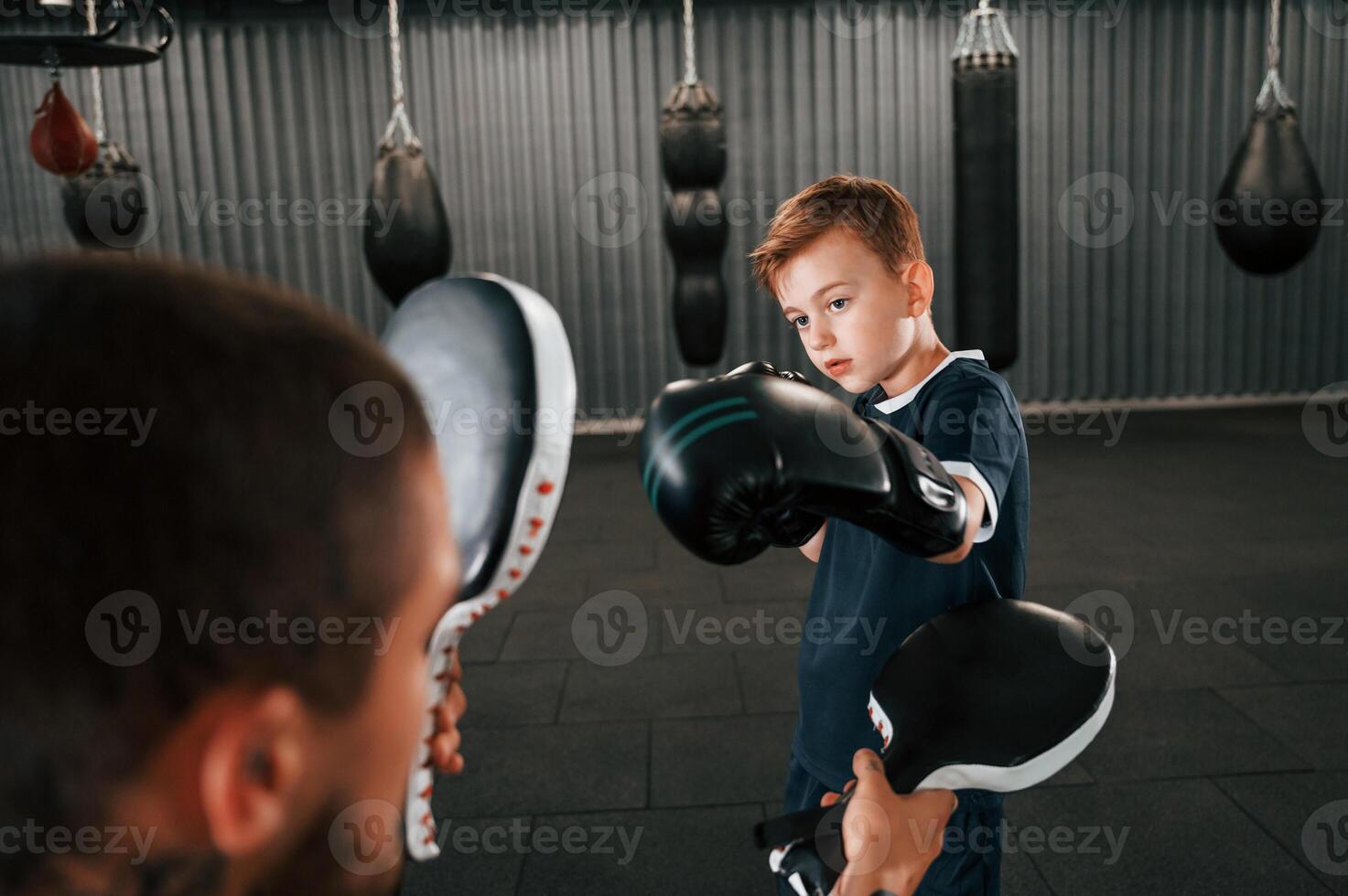 Practicing together.. Coach is teaching the boy box techniques indoors photo