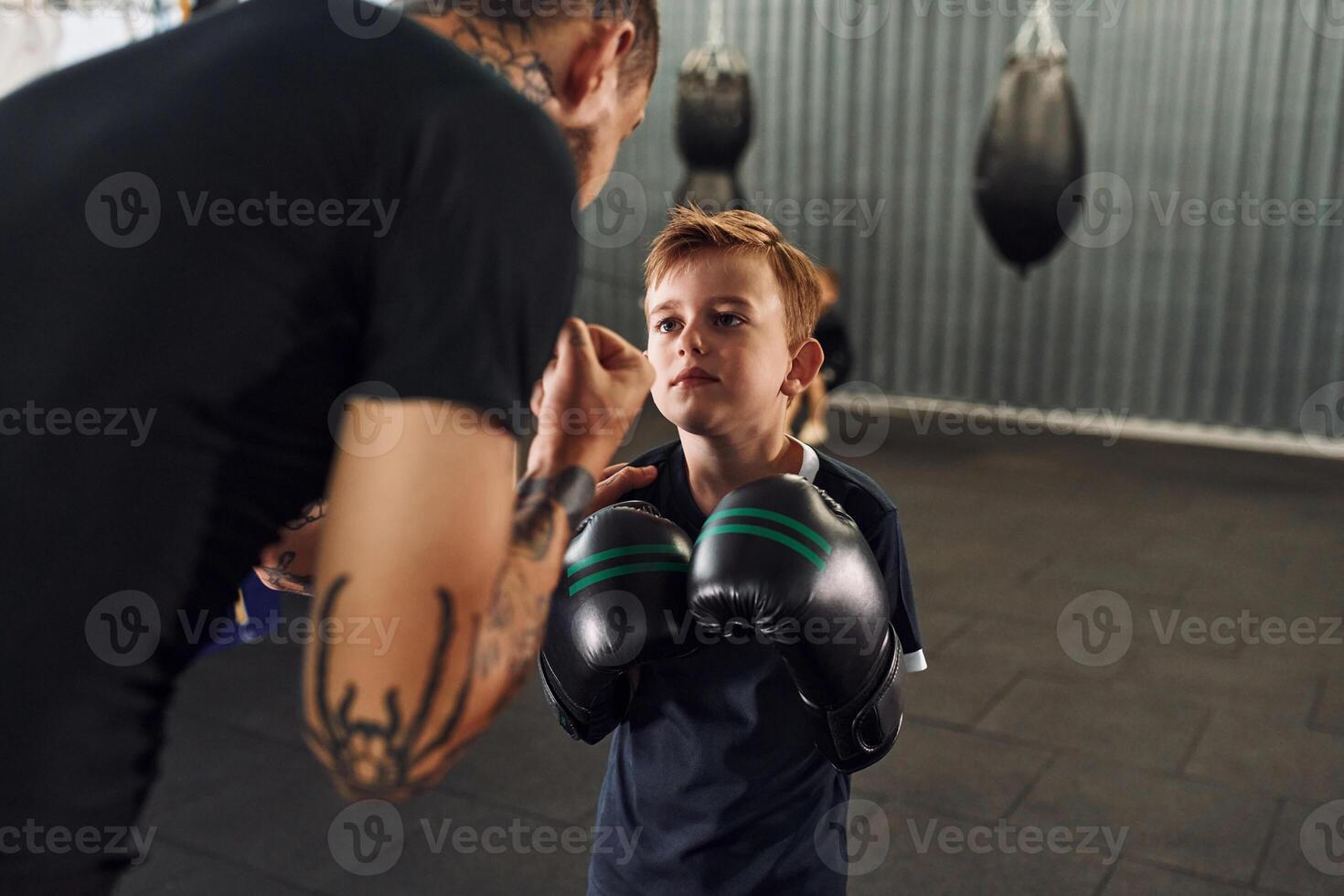 Teaching ..how to punch. Coach is with boy showing box techniques indoors photo