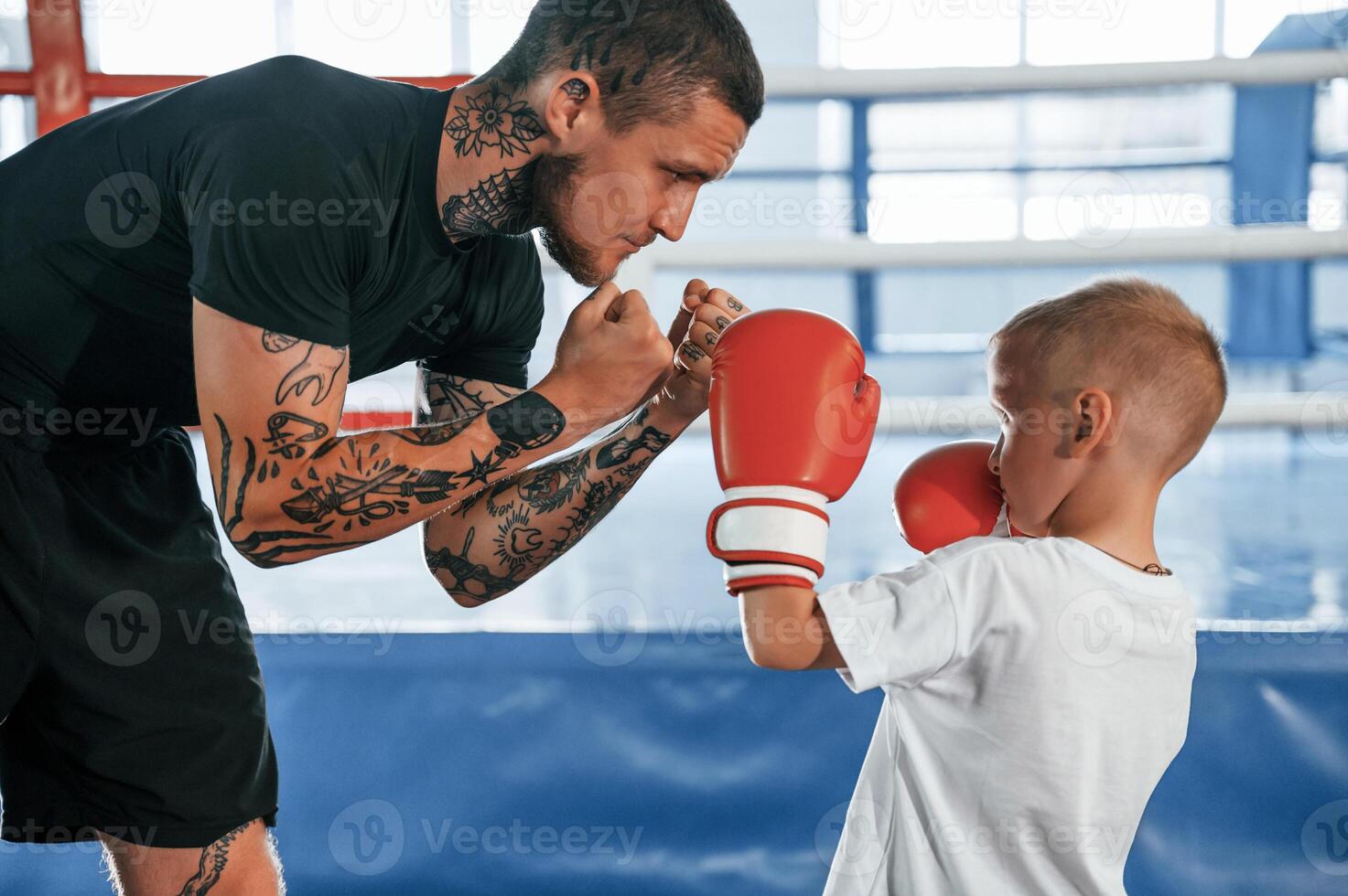 Standing and learning how to punch. Coach is teaching the boy box techniques indoors, photo