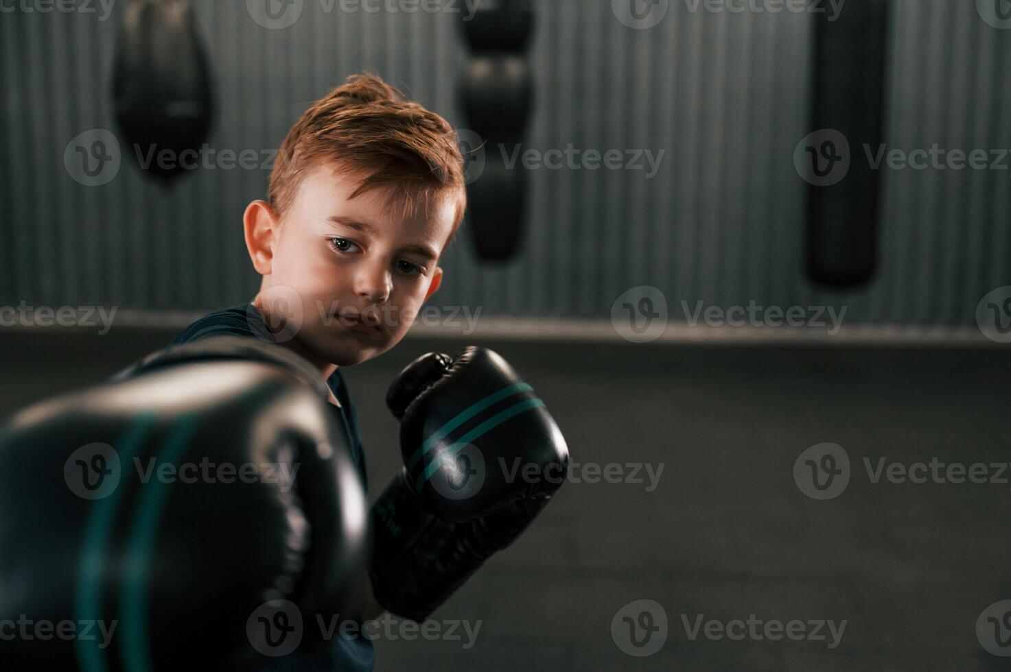 Portrait of boy that is practicing boxing in the gym with glowes on hands.. photo