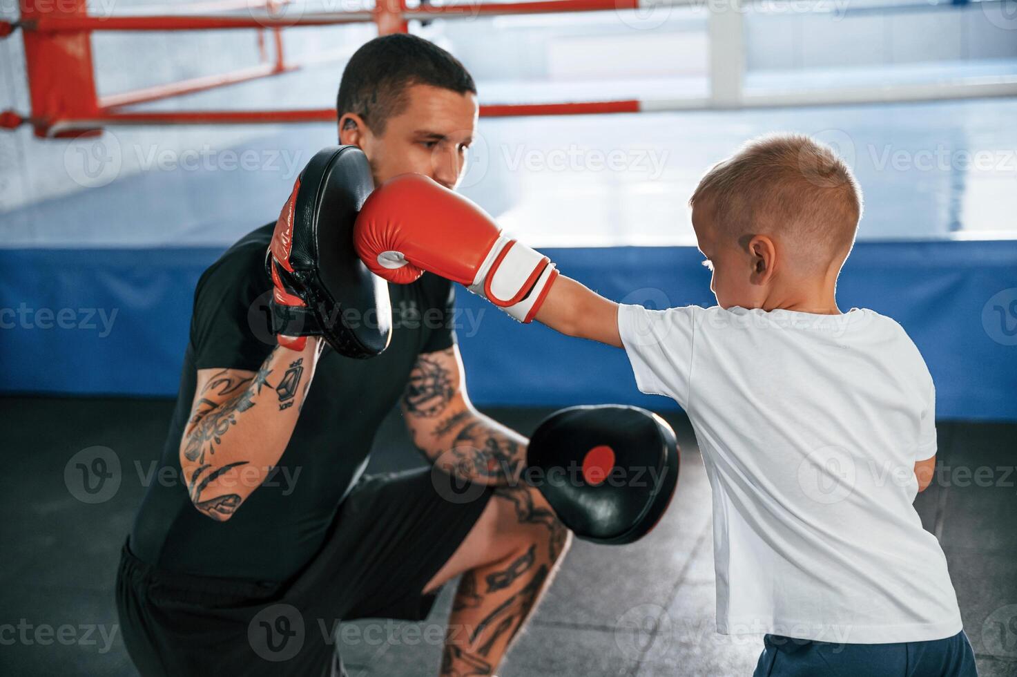 Standing and practicing the punches. Coach is teaching the boy box techniques indoors photo