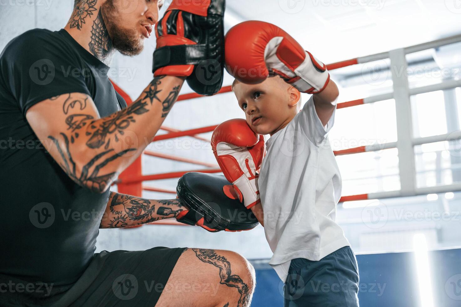 How to punch correct way. .Coach is teaching the boy box techniques indoors photo