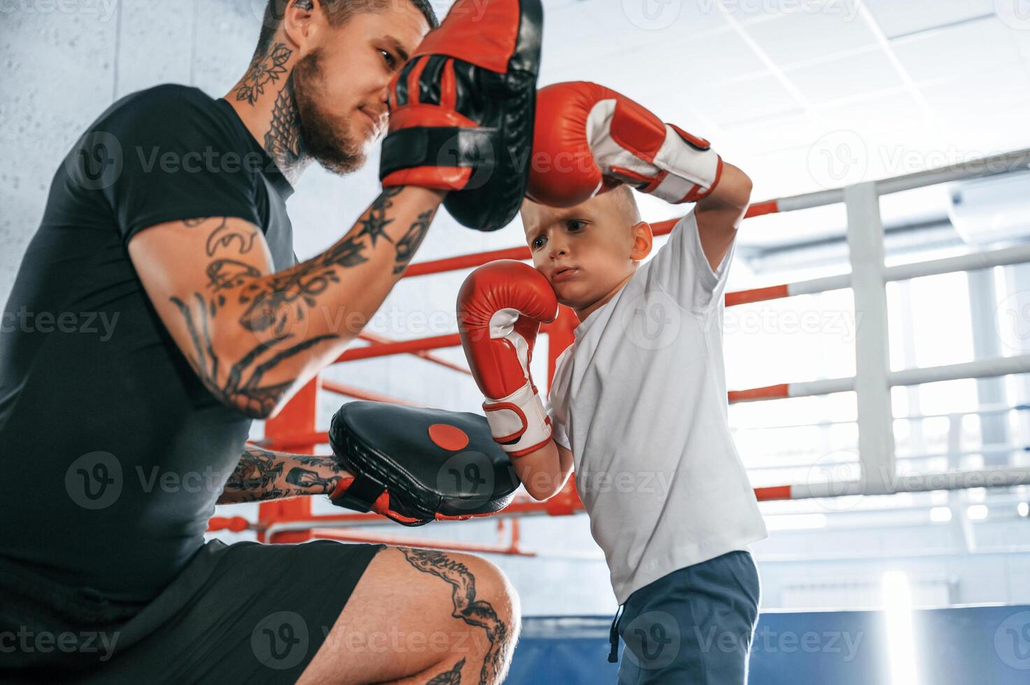 Teaching how to punch,. Coach is with boy showing box techniques indoors photo