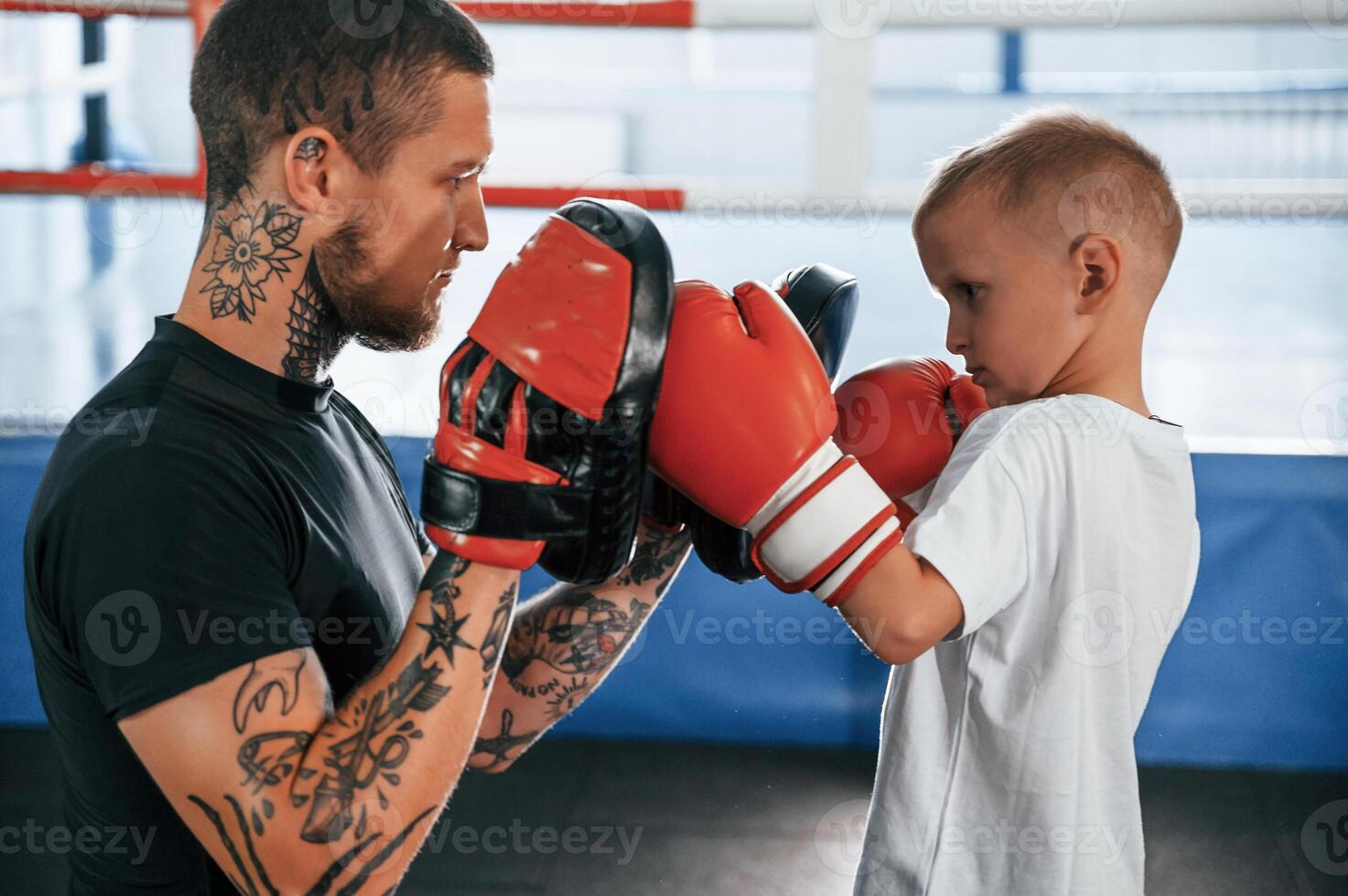 How to punch correct way., Coach is teaching the boy box techniques indoors photo