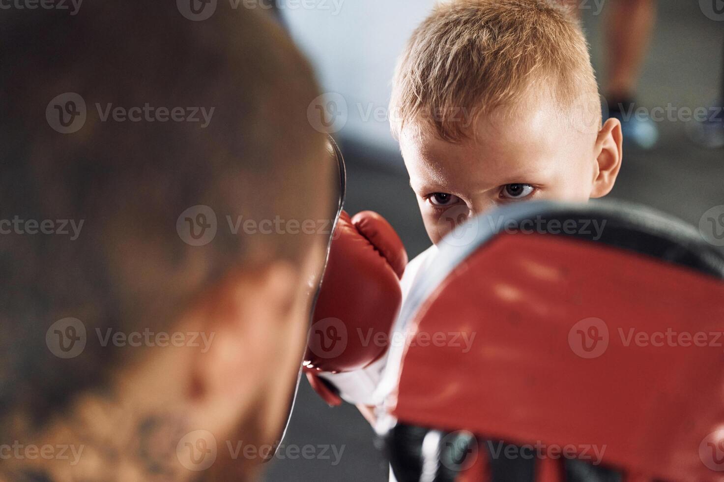 How to punch correct way. Coach is teaching the boy box techniques indoors photo