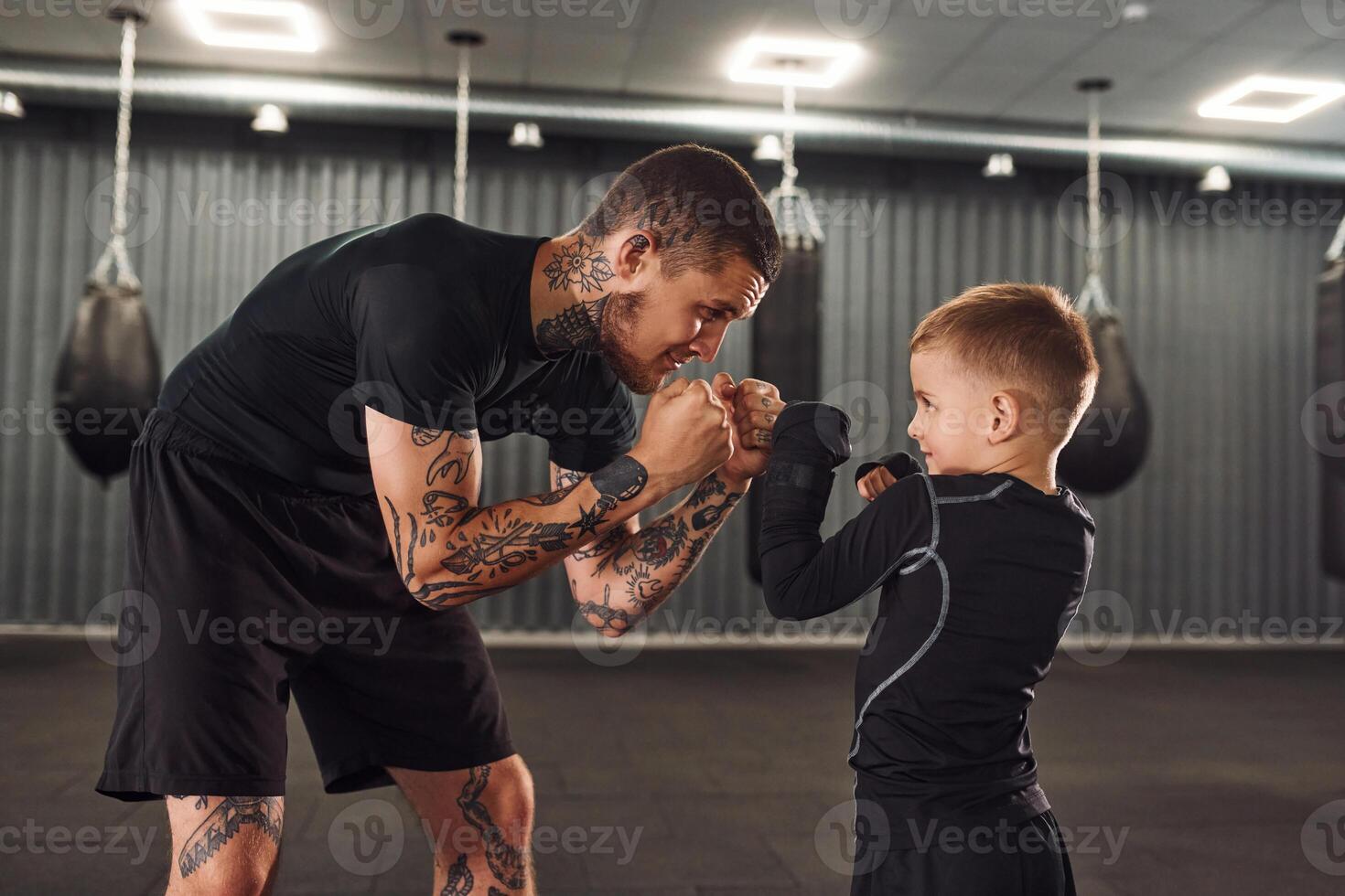 Side view... Coach is teaching the boy box techniques indoors photo