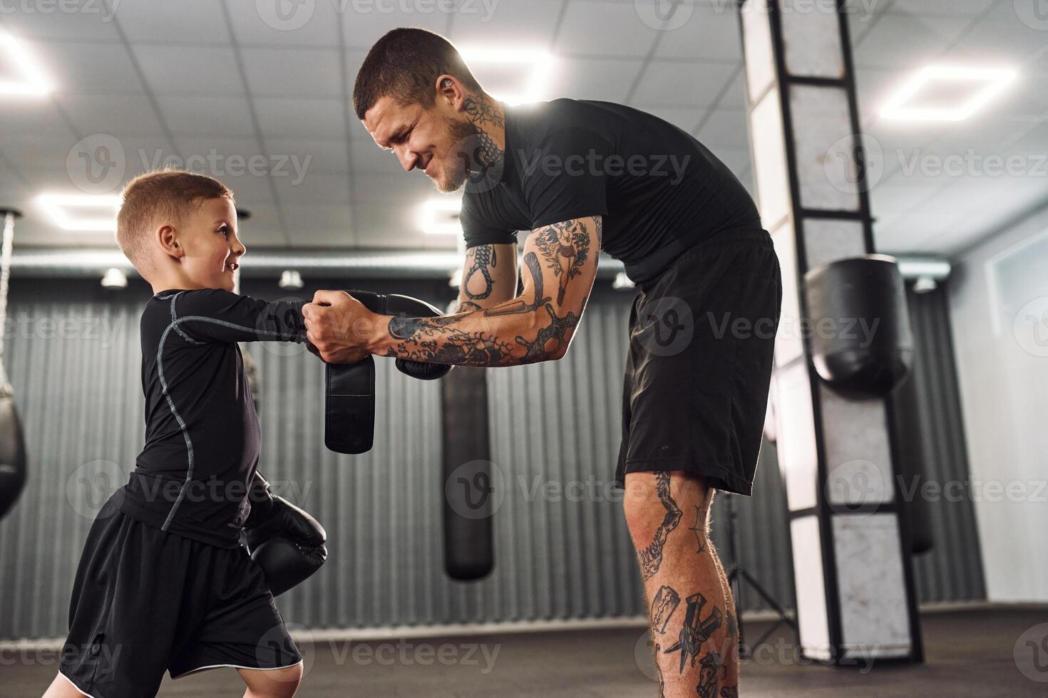 Standing and learning how to punch. .Coach is teaching the boy box techniques indoors photo