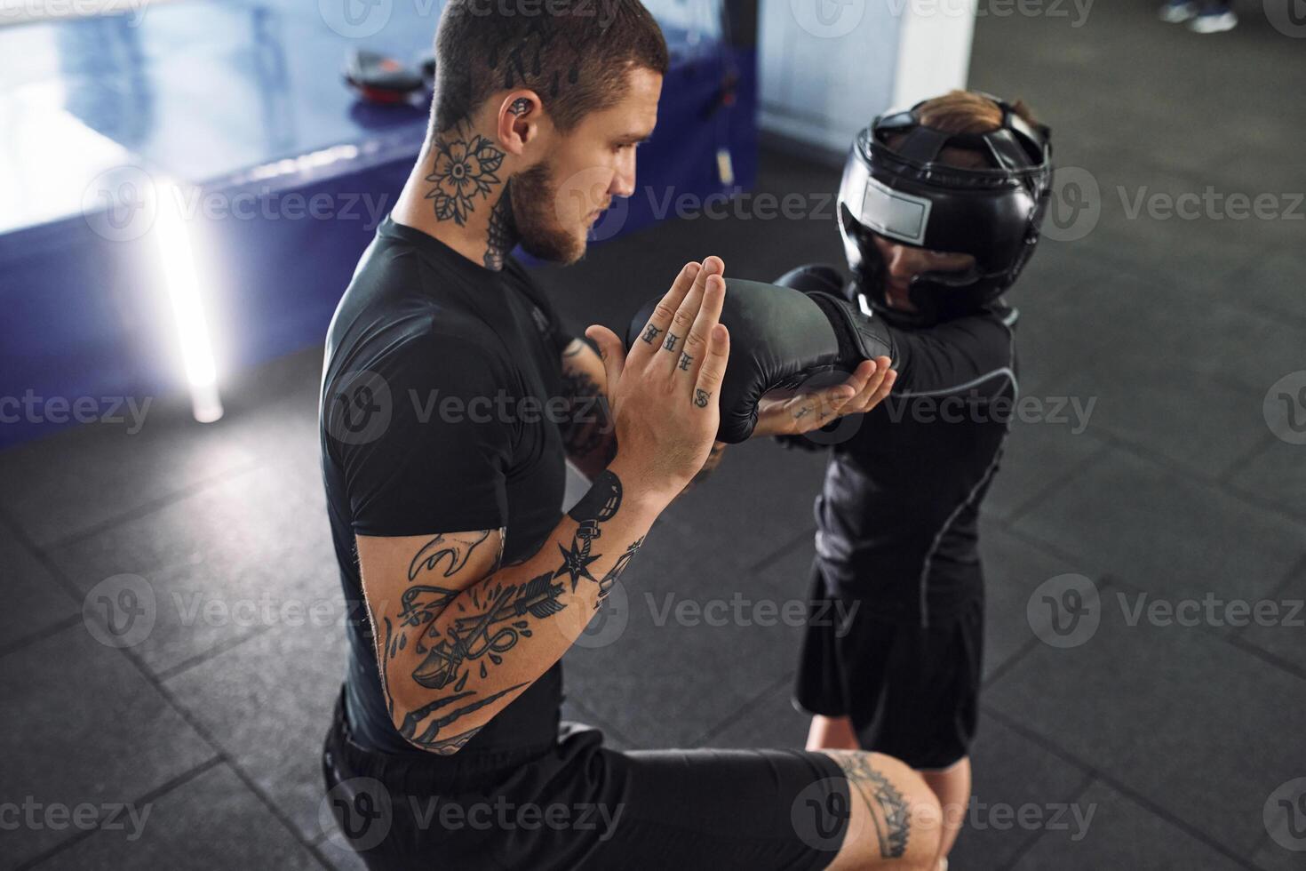 Learning process. Punching the hand. Coach is teaching the boy box techniques indoors photo