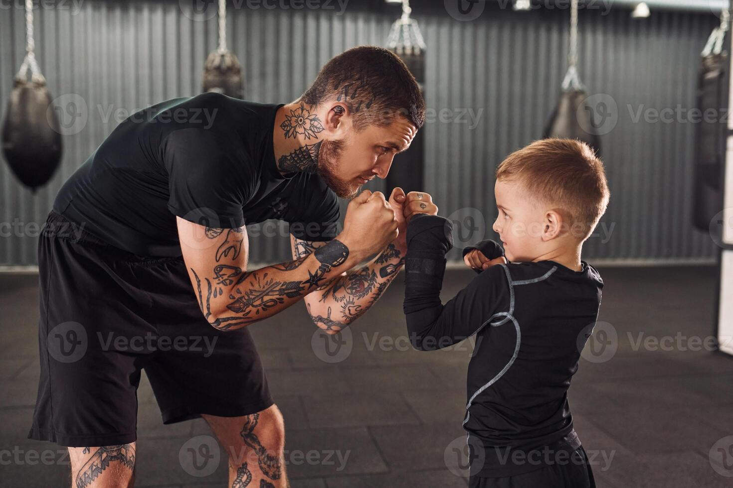 Side view. .Coach is teaching the boy box techniques indoors photo