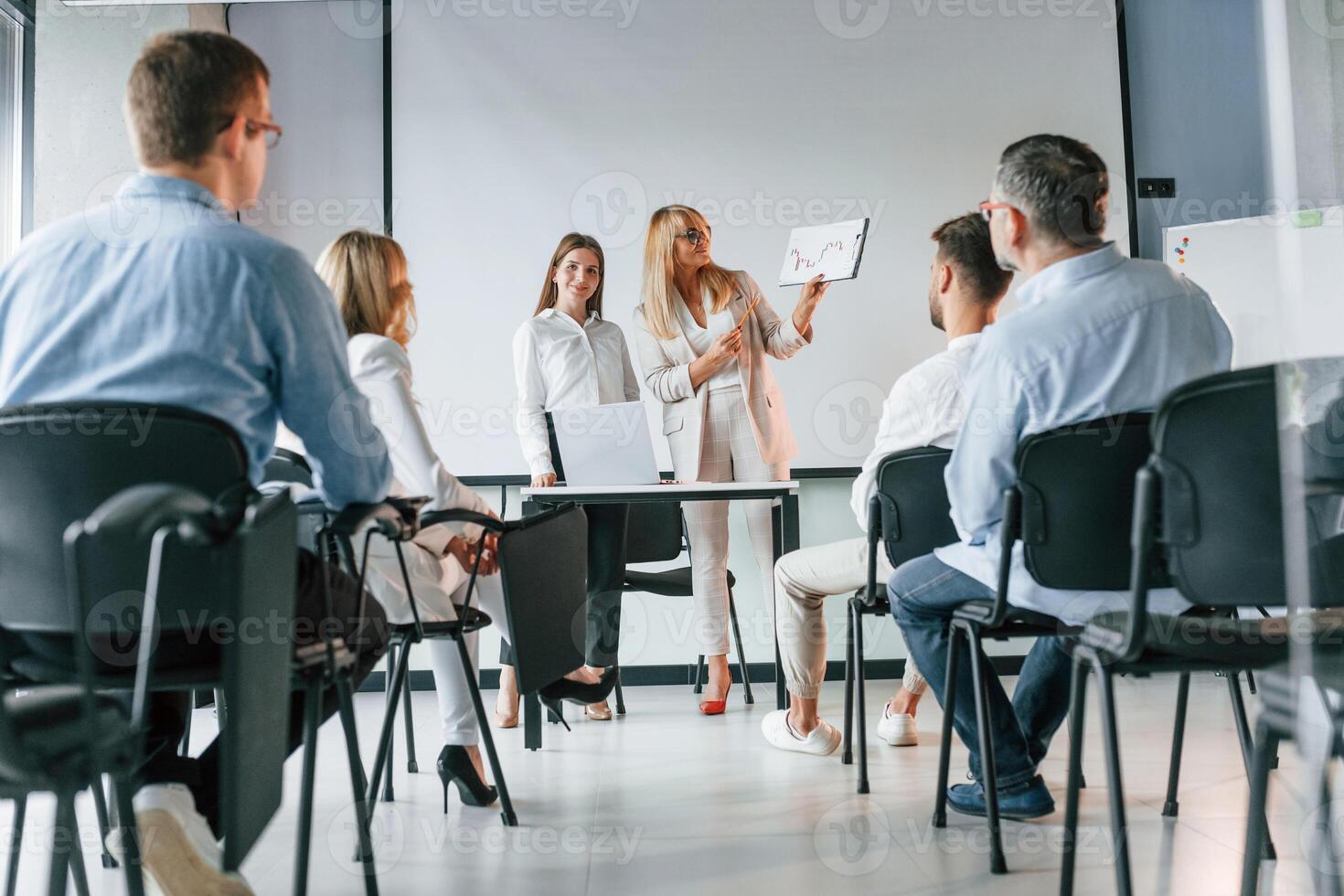 Sitting and learning new stuff from woman.. Group of professional business people is in the office photo