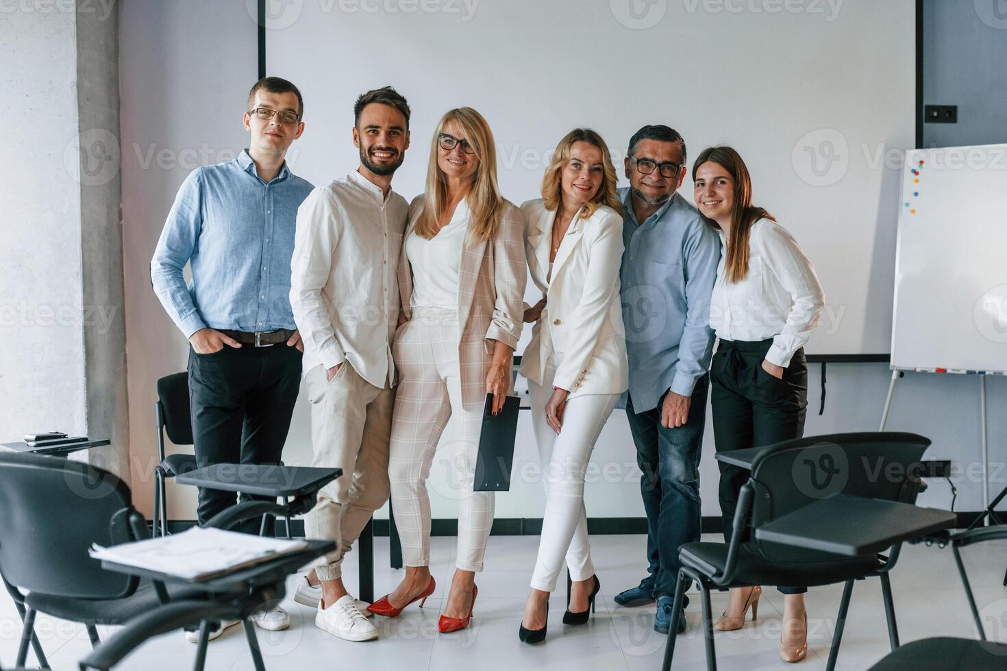Standing and posing for a camera in the class. Group of professional business people is in the office photo