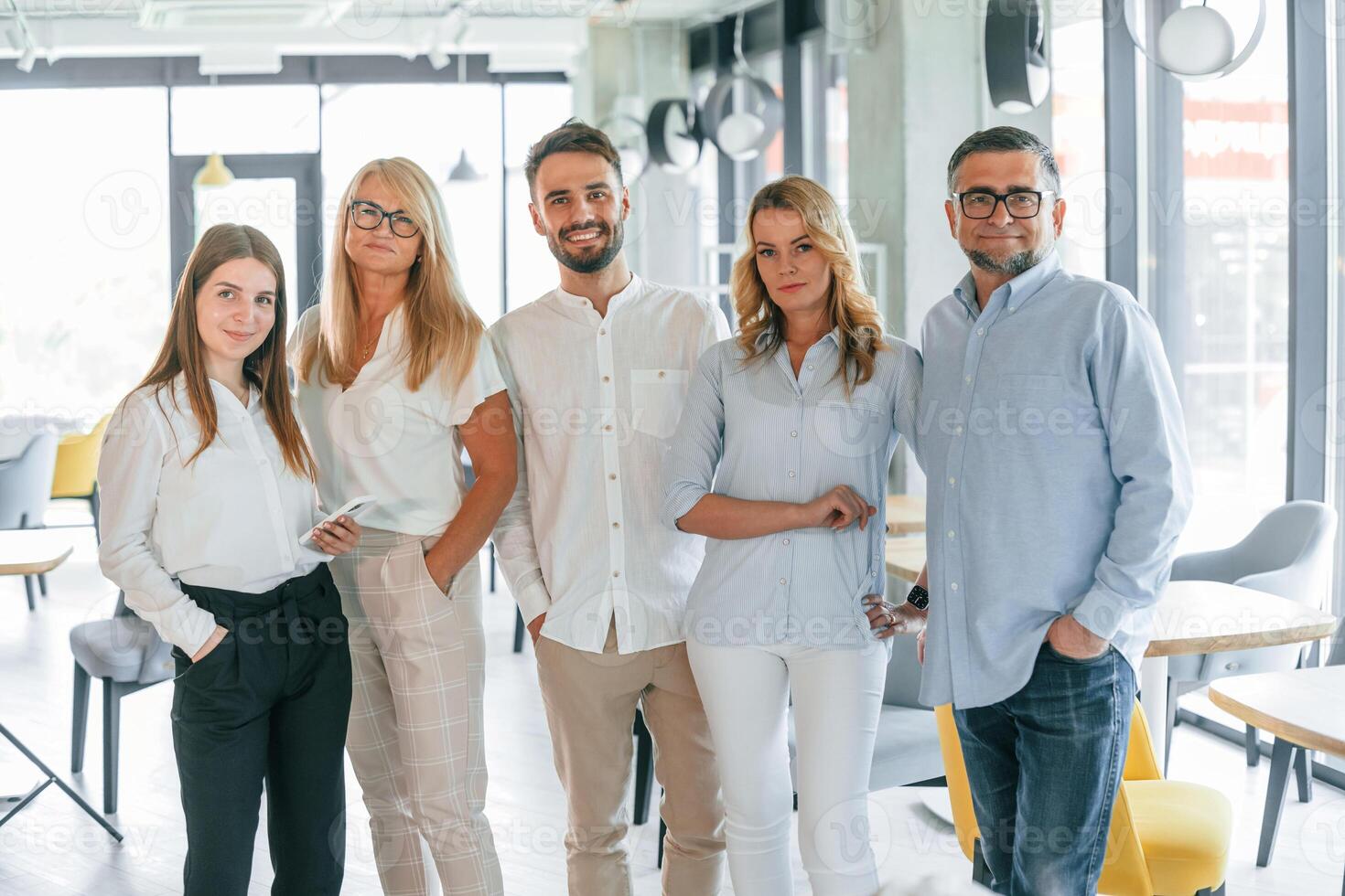 Standing together and posing for a camera. Group of professional business people is in the office photo