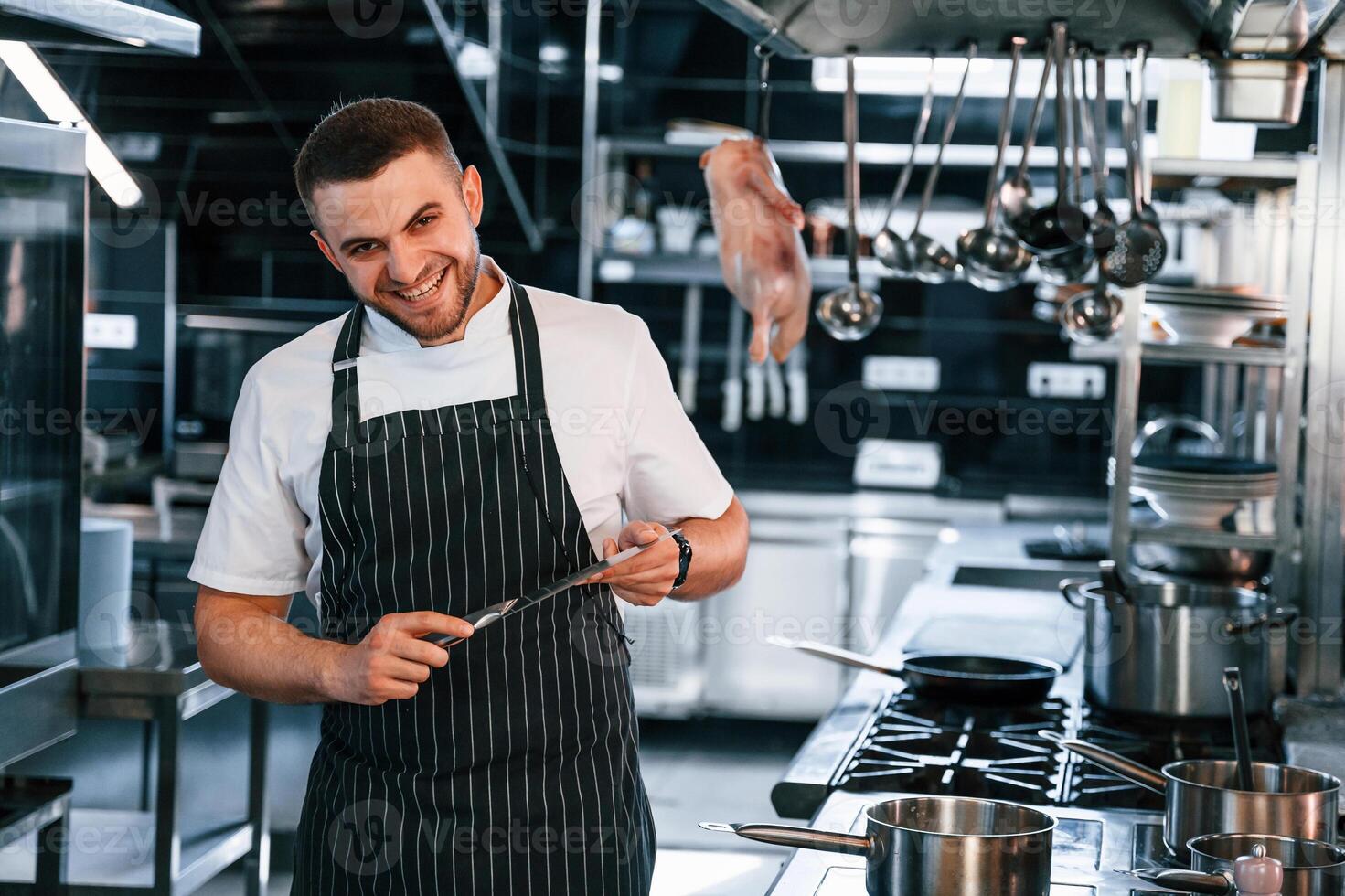 Standing and looking at the camera. Chef is on the kitchen preparing food.,. photo