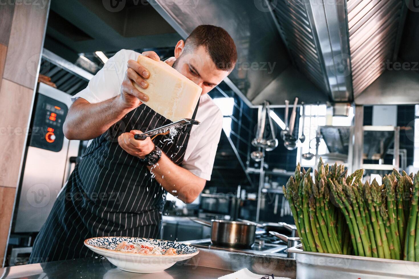 Adding cheese. Chef is on the kitchen preparing food photo
