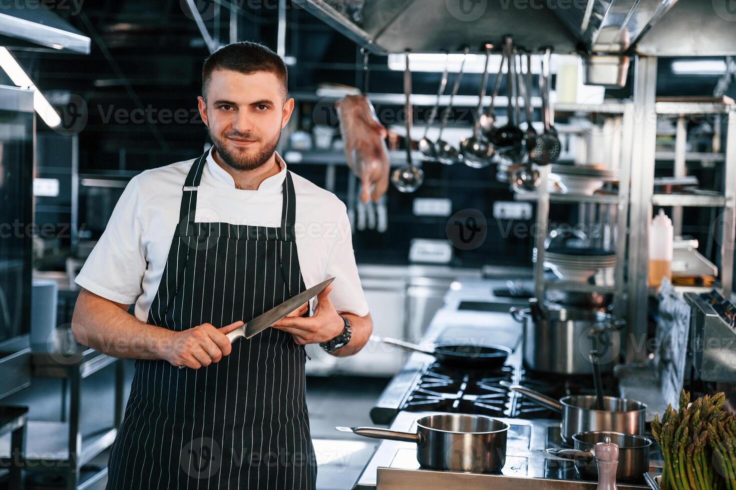 Standing and looking at the camera. Chef is on the kitchen preparing food. photo