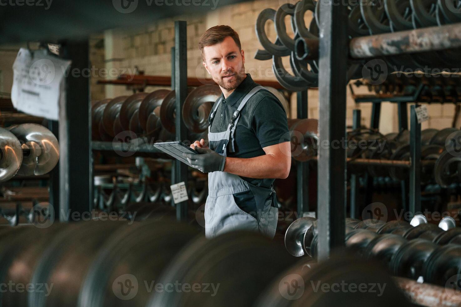 Manager, is using digital tablet. Man in uniform is in workstation developing details of agriculture technique photo