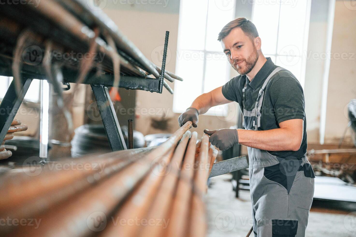 Measuring lenght of metal pieces. .Man in uniform is in workstation developing details of agriculture technique photo
