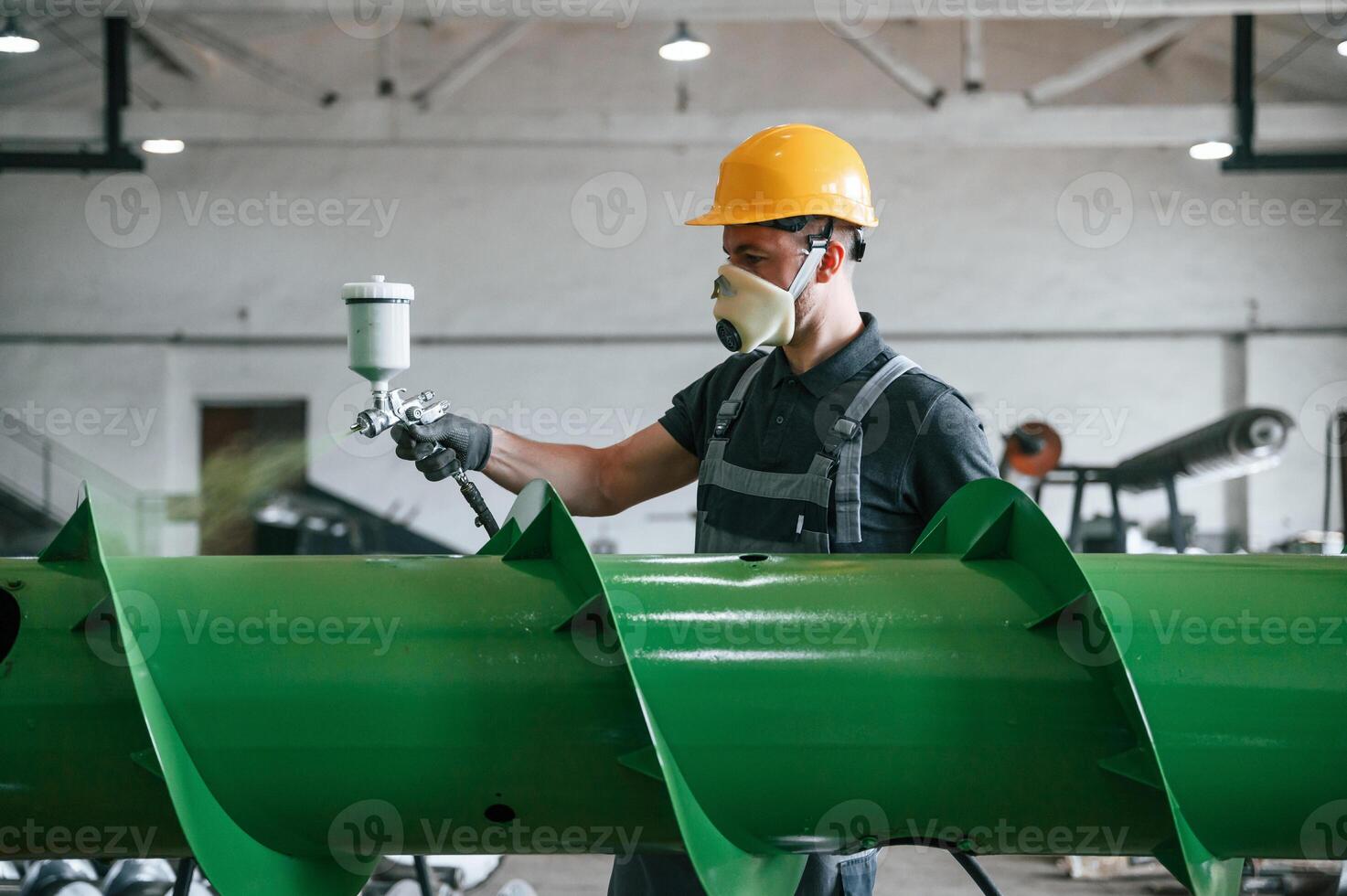 Painting details. Man in uniform is in workstation developing details of agriculture technique. photo