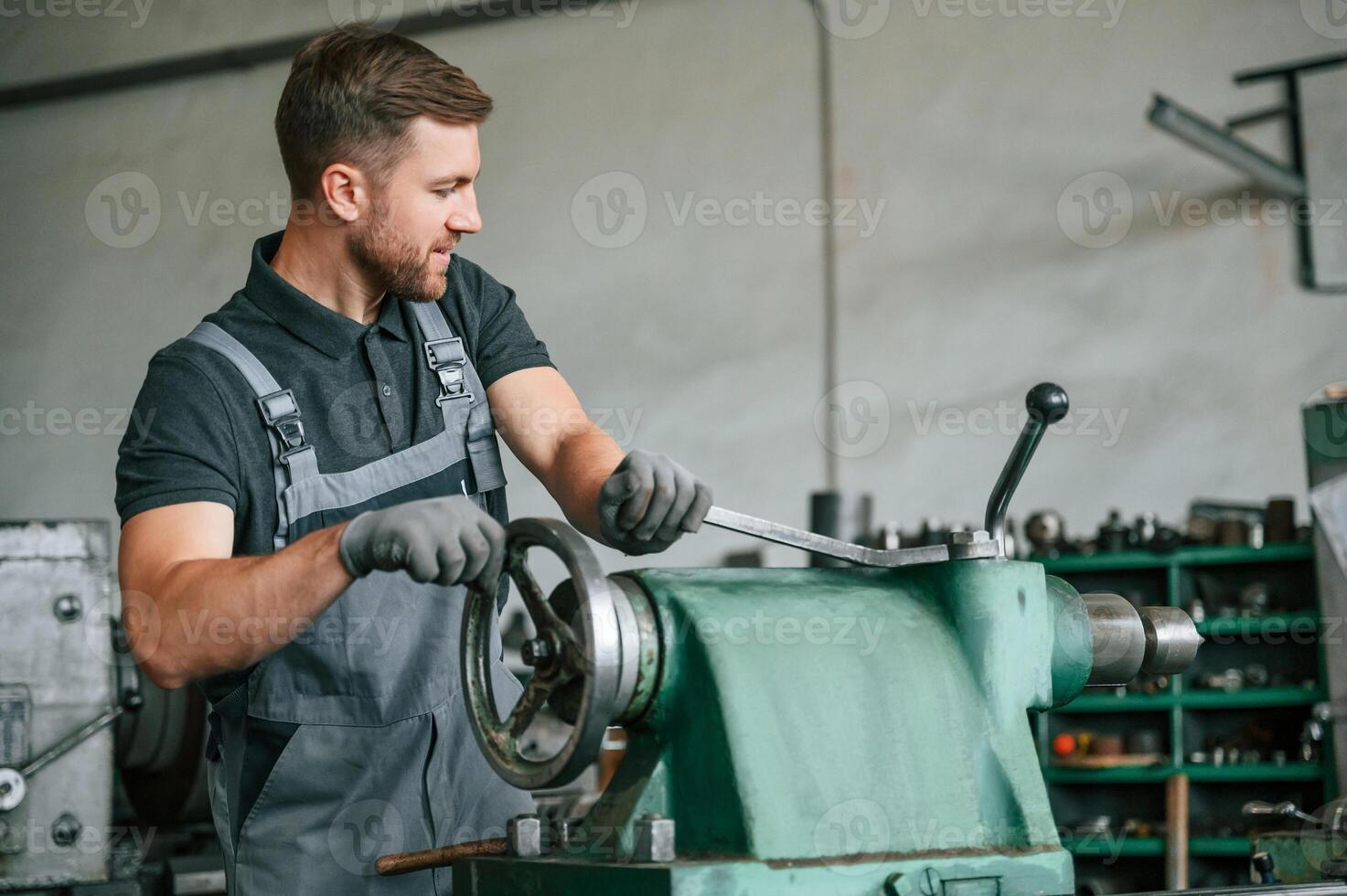 Operating ,manufacturing equipment. Man in uniform is in workstation developing details of agriculture technique photo