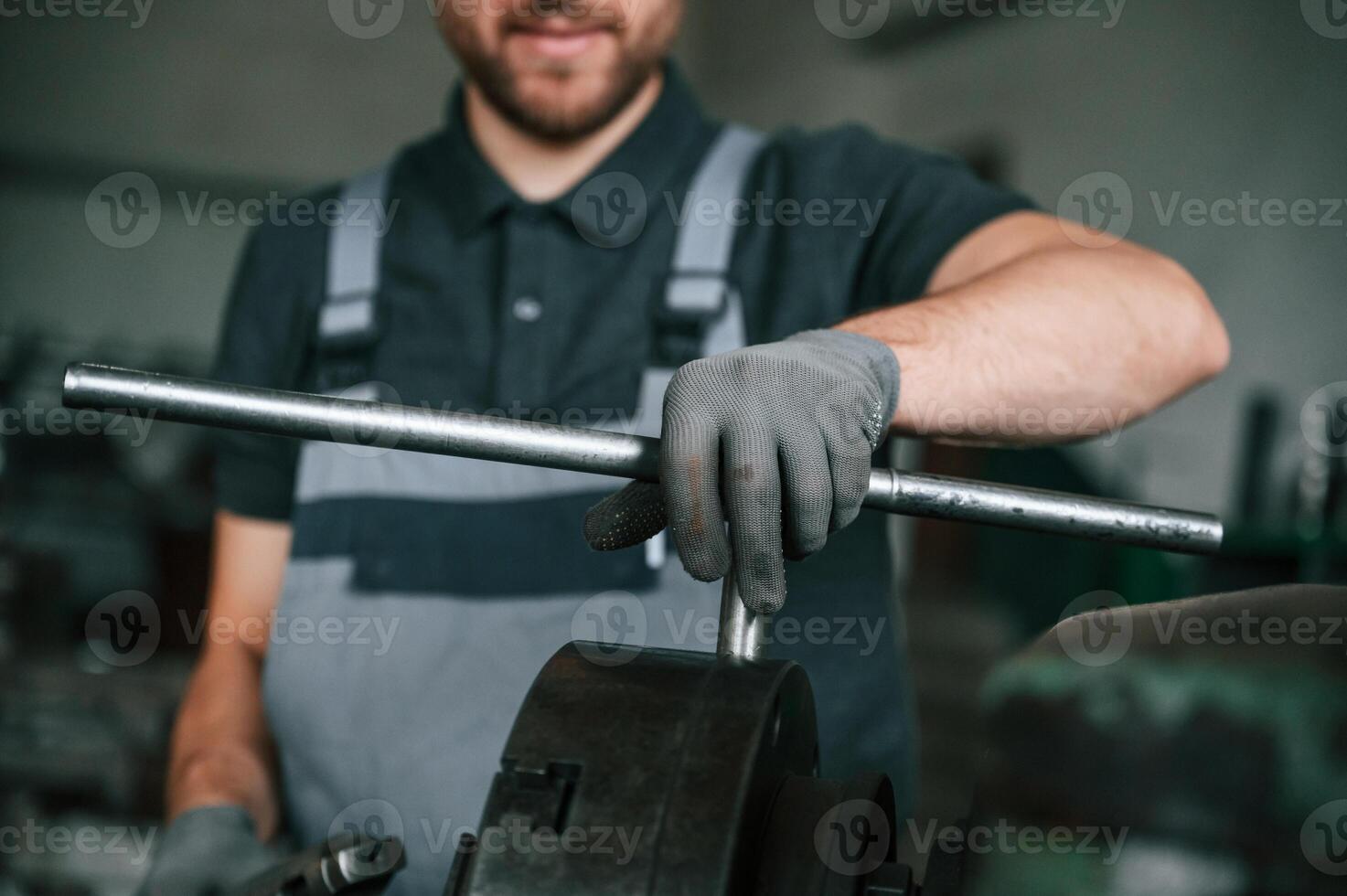 Focused, on the developing the parts. Man in uniform is in workstation developing details of agriculture technique photo