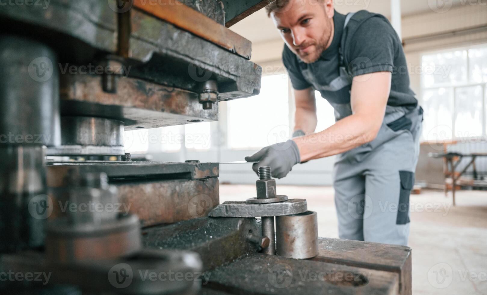 Operating, manufacturing equipment. Man in uniform is in workstation developing details of agriculture technique photo