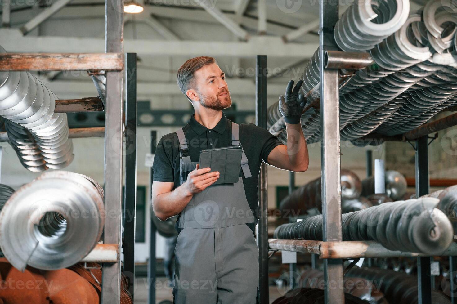 Holding tablet.. Man in uniform is in workstation developing details of agriculture technique photo
