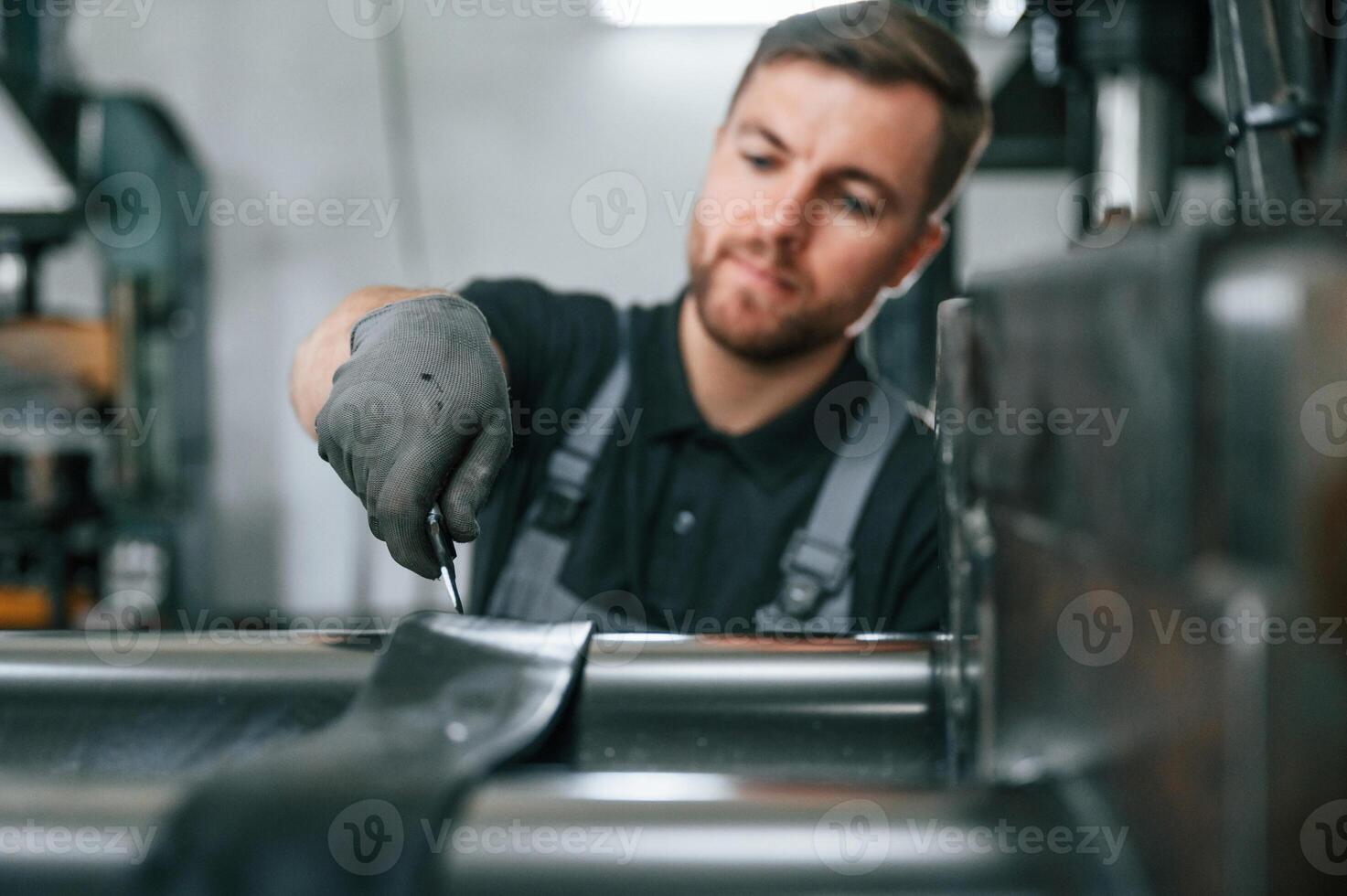 Clean parts. Man in uniform is in workstation developing details of agriculture technique. photo