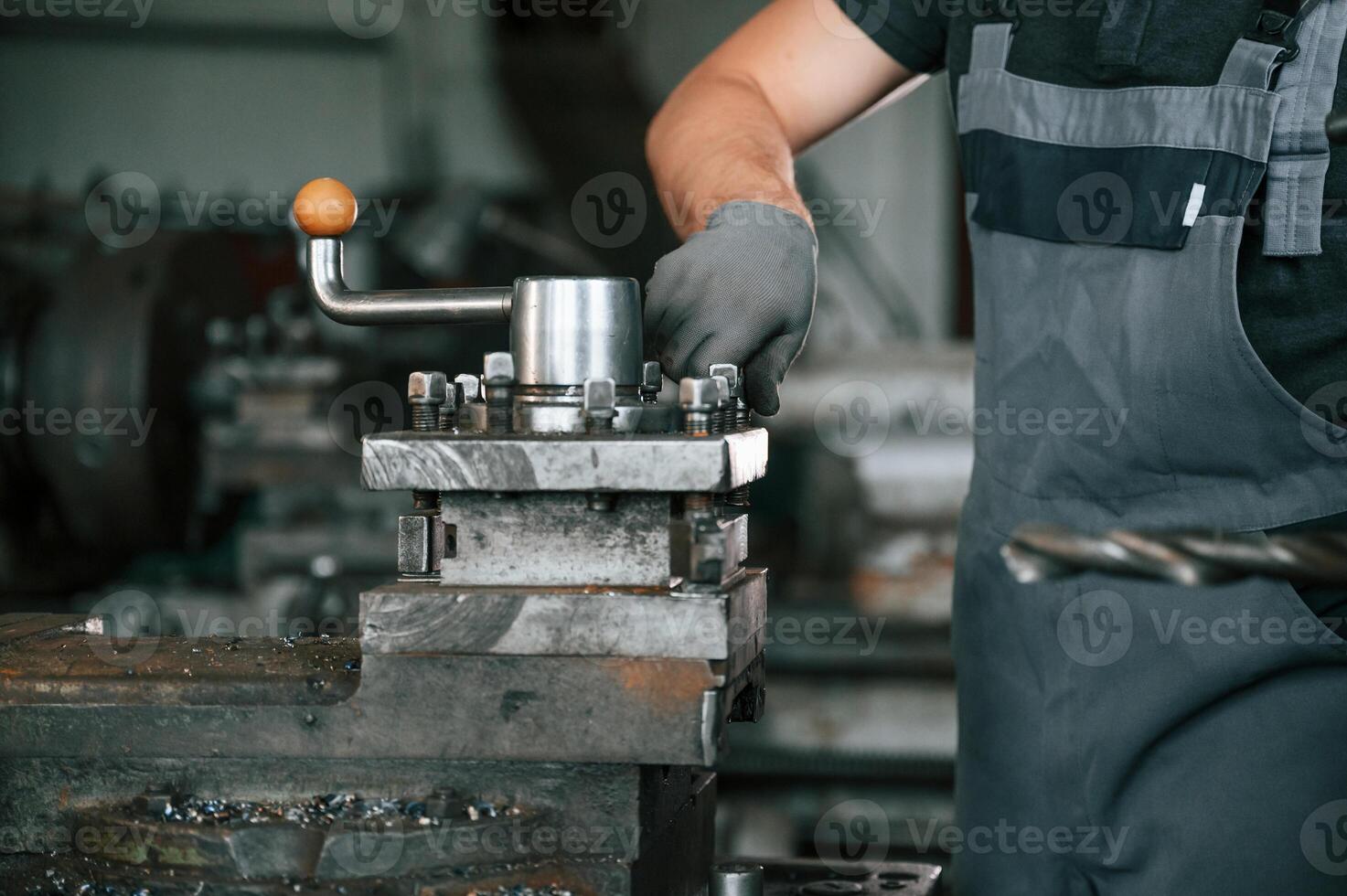 Focused on the developing the parts. Man in uniform is in workstation developing details of agriculture technique photo