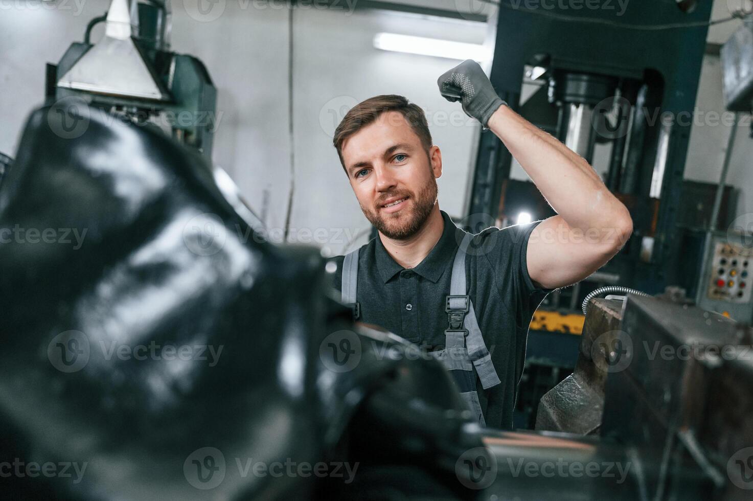 Clean parts.. Man in uniform is in workstation developing details of agriculture technique photo