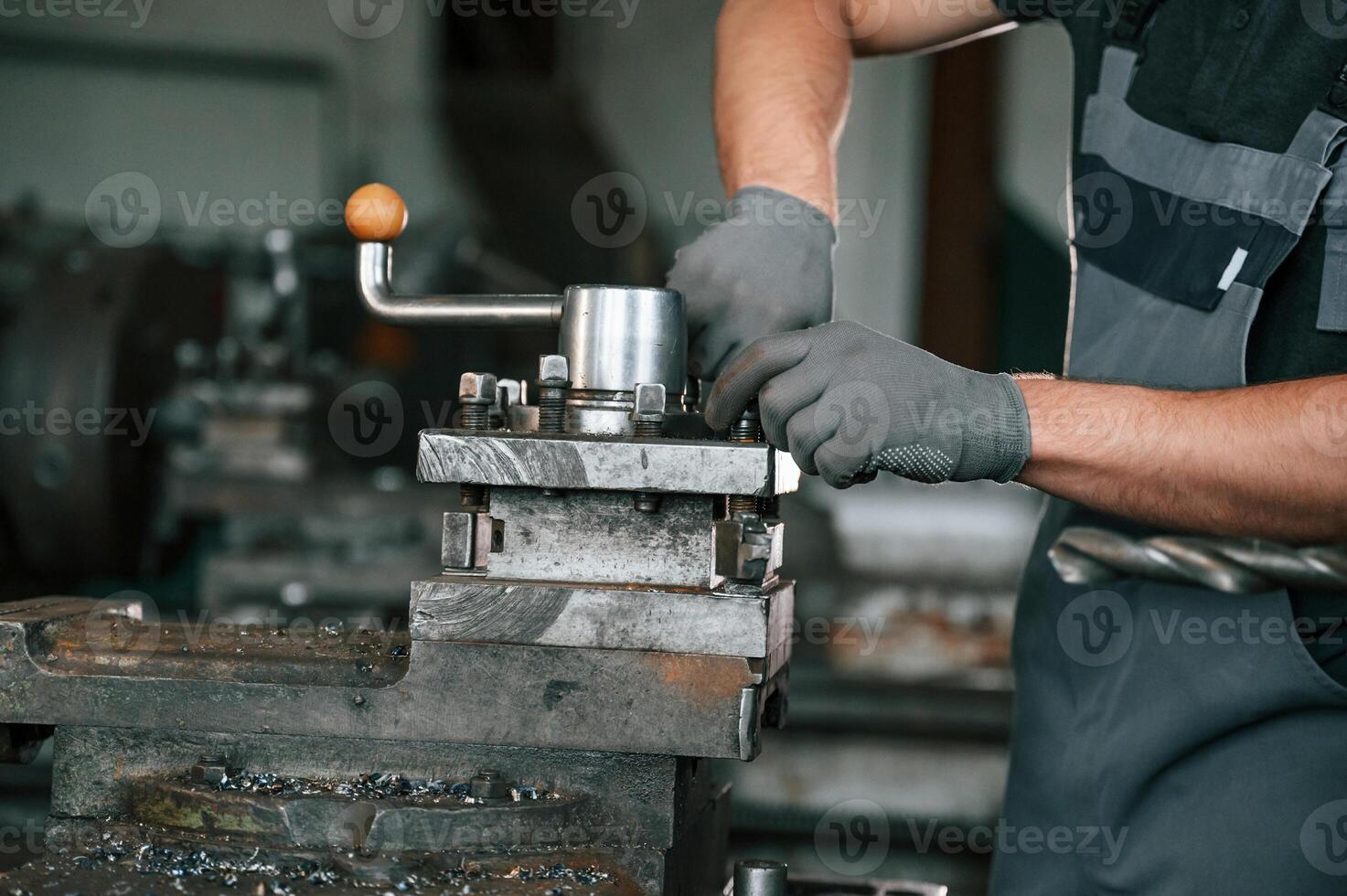 Focused ,on the developing the parts. Man in uniform is in workstation developing details of agriculture technique photo