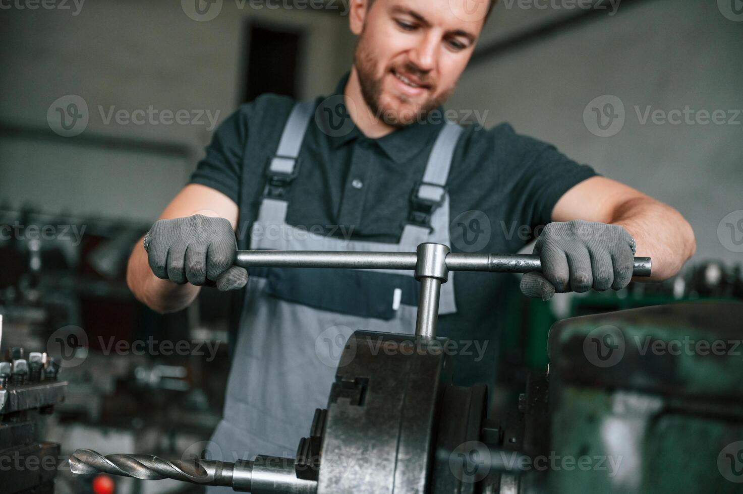 Focused on the developing the parts.. Man in uniform is in workstation developing details of agriculture technique photo