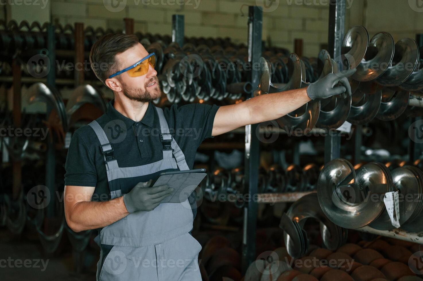 Standing with tablet. Man in uniform is in workstation developing details of agriculture technique photo