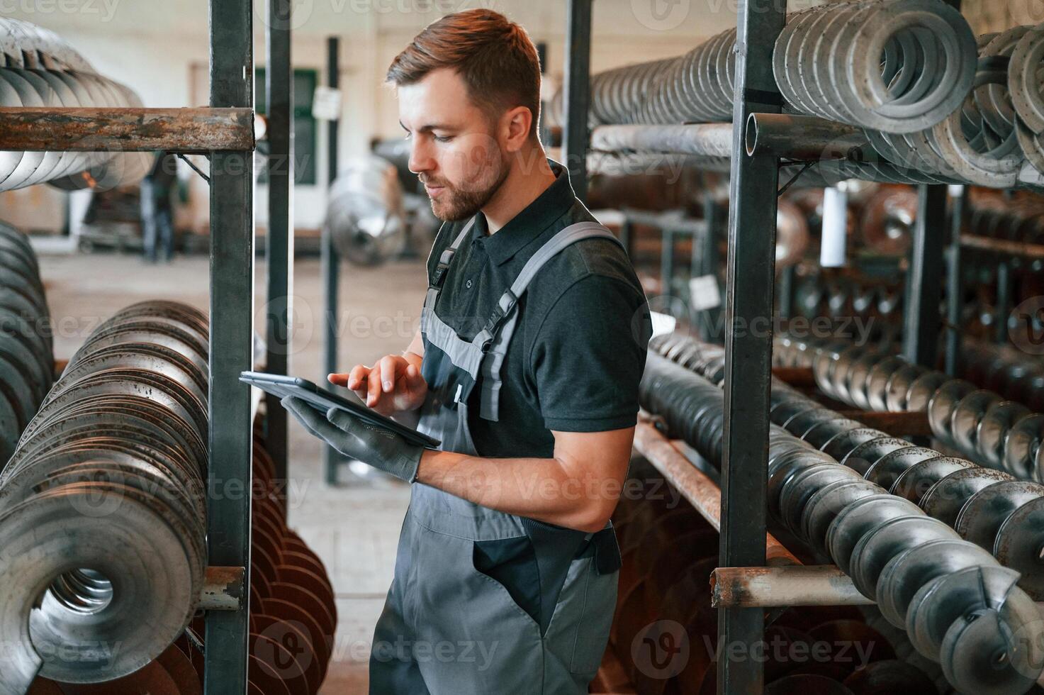 Checking details.. Man in uniform is in workstation developing details of agriculture technique photo