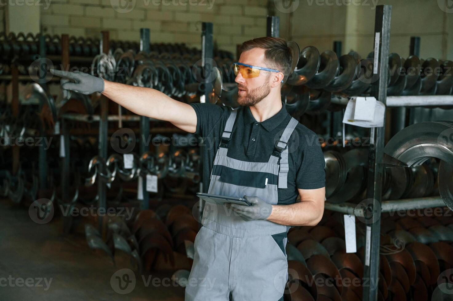 Standing with tablet. Man in uniform is in workstation developing details of agriculture technique. photo