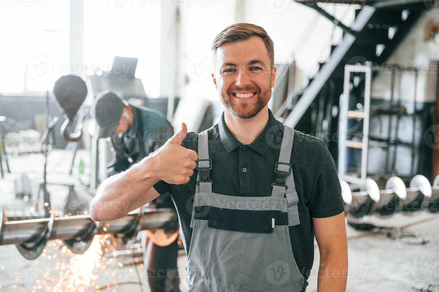 Standing and smiling. Man in uniform is in workstation developing details of agriculture technique photo