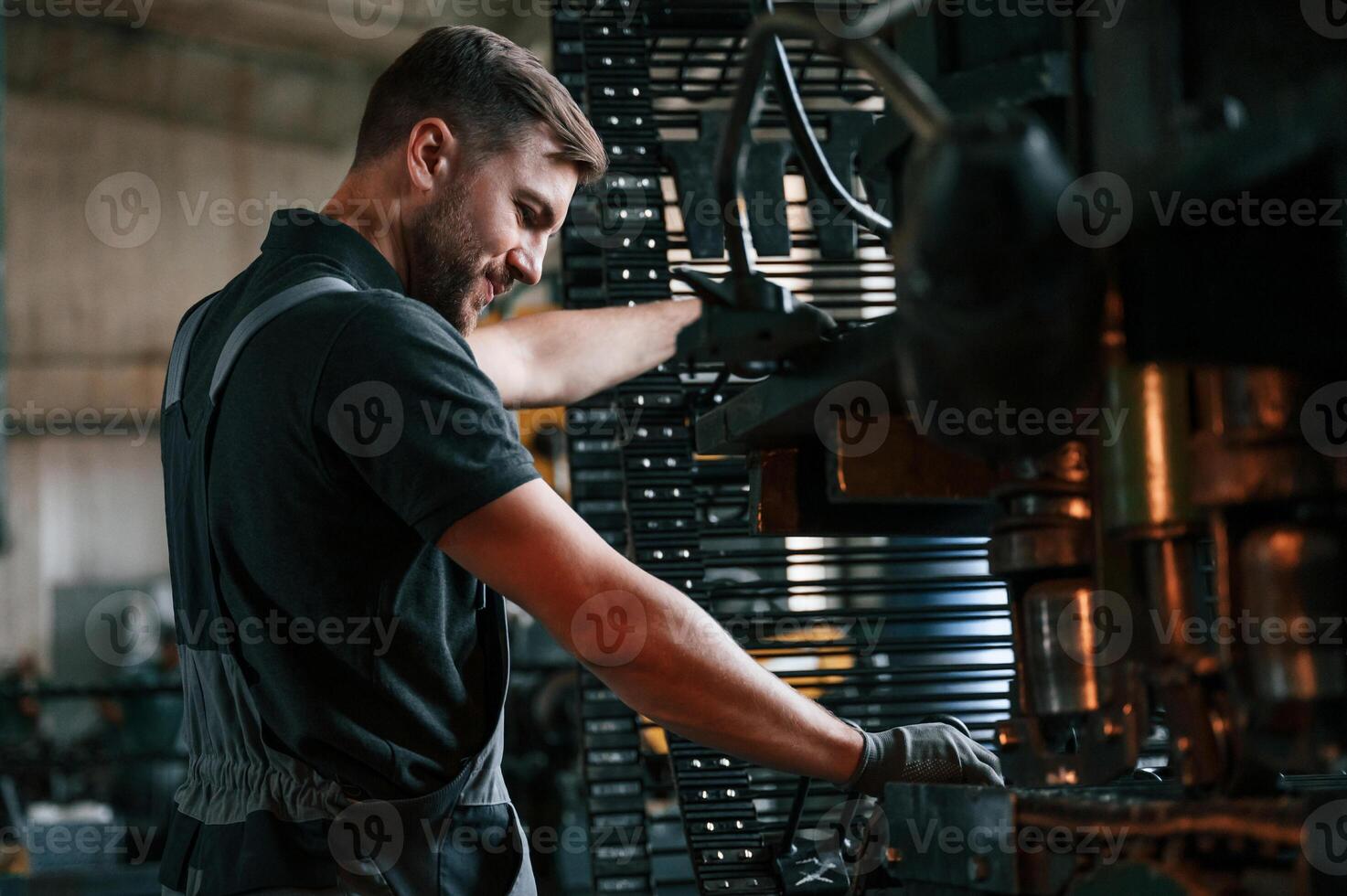 Metal processing device. Man in uniform is in workstation developing details of agriculture technique., photo