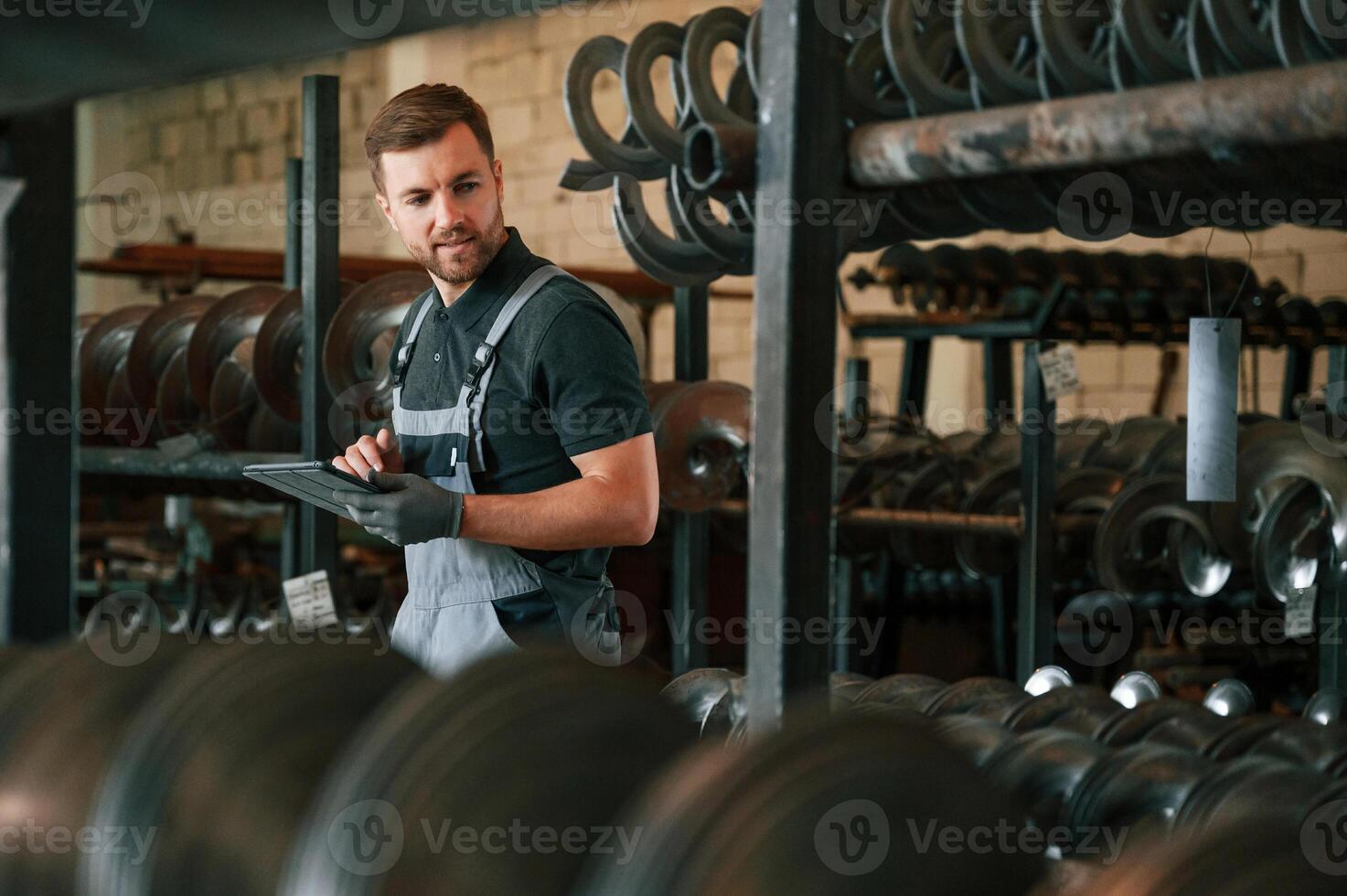 Manager,. is using digital tablet. Man in uniform is in workstation developing details of agriculture technique photo