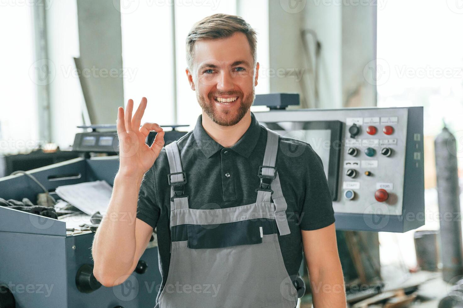 Standing near operate device. Man in uniform is in workstation developing details of agriculture technique photo