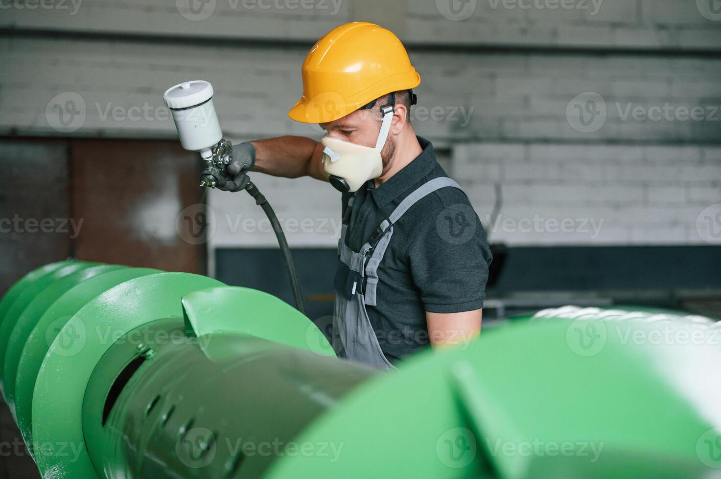 In, protective mask. Painting details. Man in uniform is in workstation developing details of agriculture technique photo