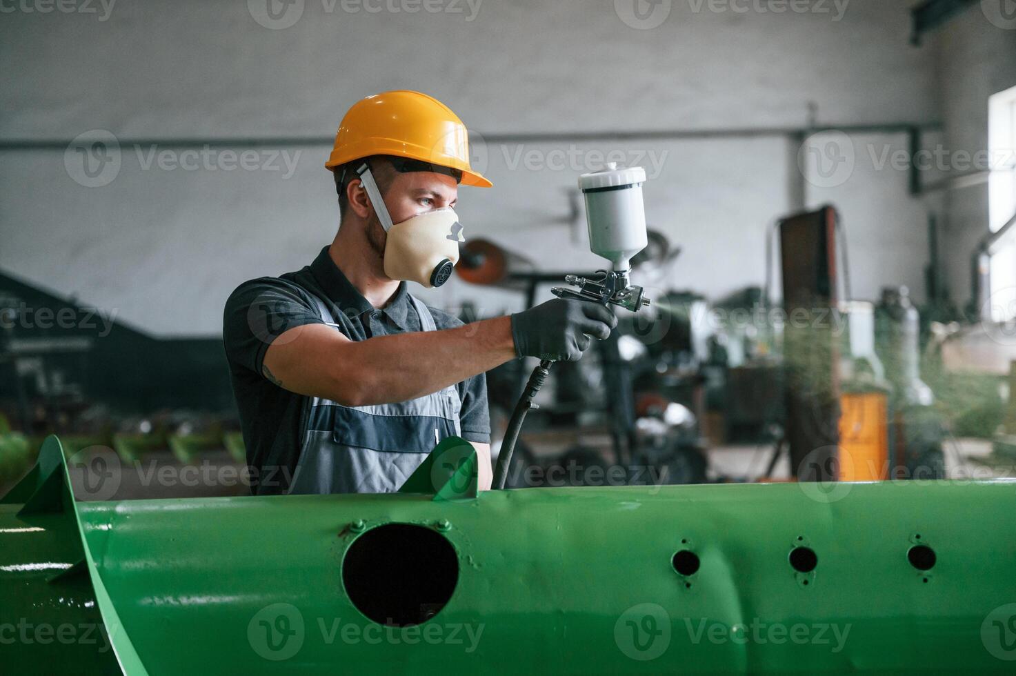 Painting details. Man in uniform is in workstation developing details of agriculture technique photo