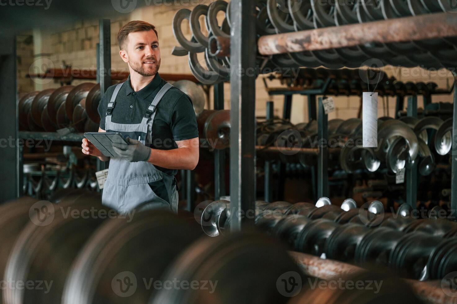 Checking quality of the products. Man in uniform is in workstation developing details of agriculture technique photo