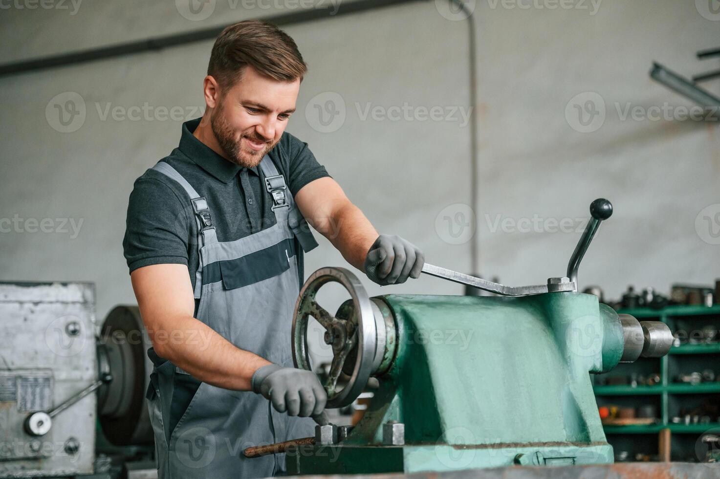 Operating manufacturing equipment. Man in uniform is in workstation developing details of agriculture technique, photo