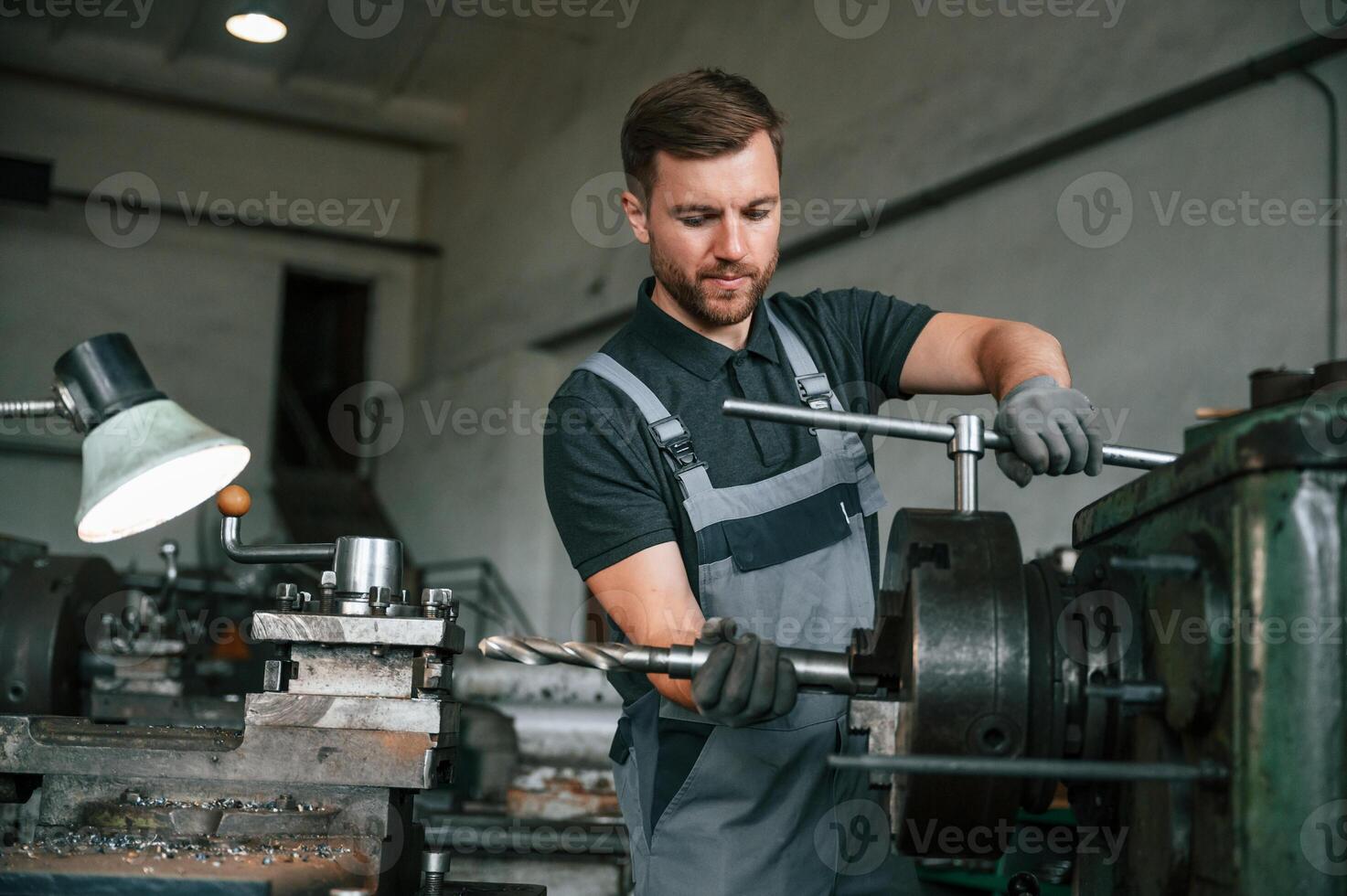 Crafting details.. Man in uniform is in workstation developing details of agriculture technique photo